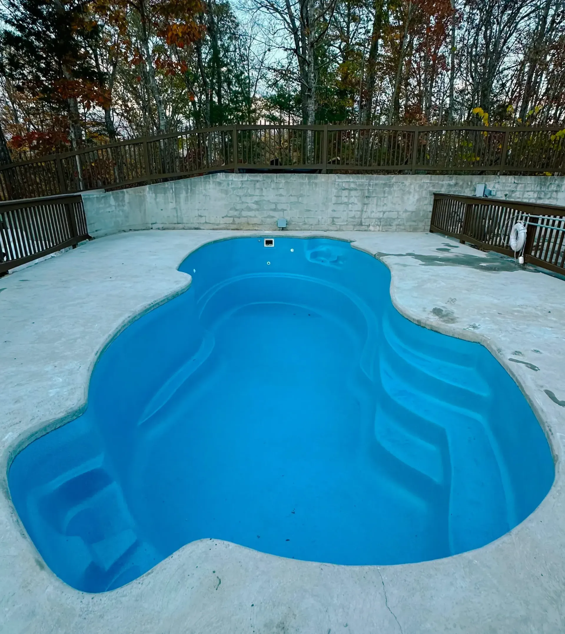 A large swimming pool is surrounded by chairs on a deck