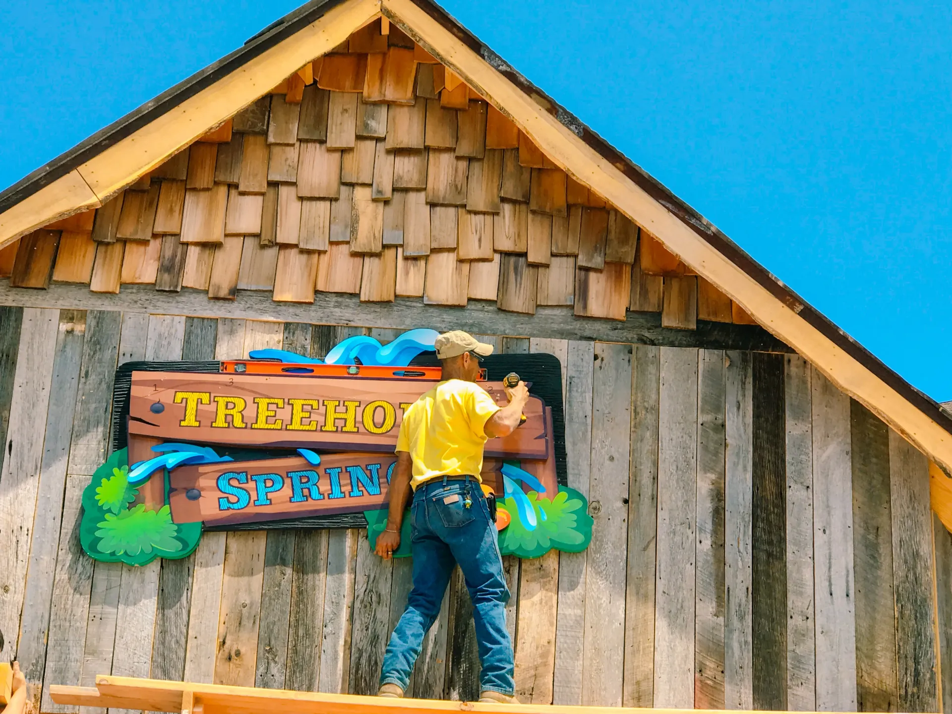 A man standing in front of a sign that says treehouse spring