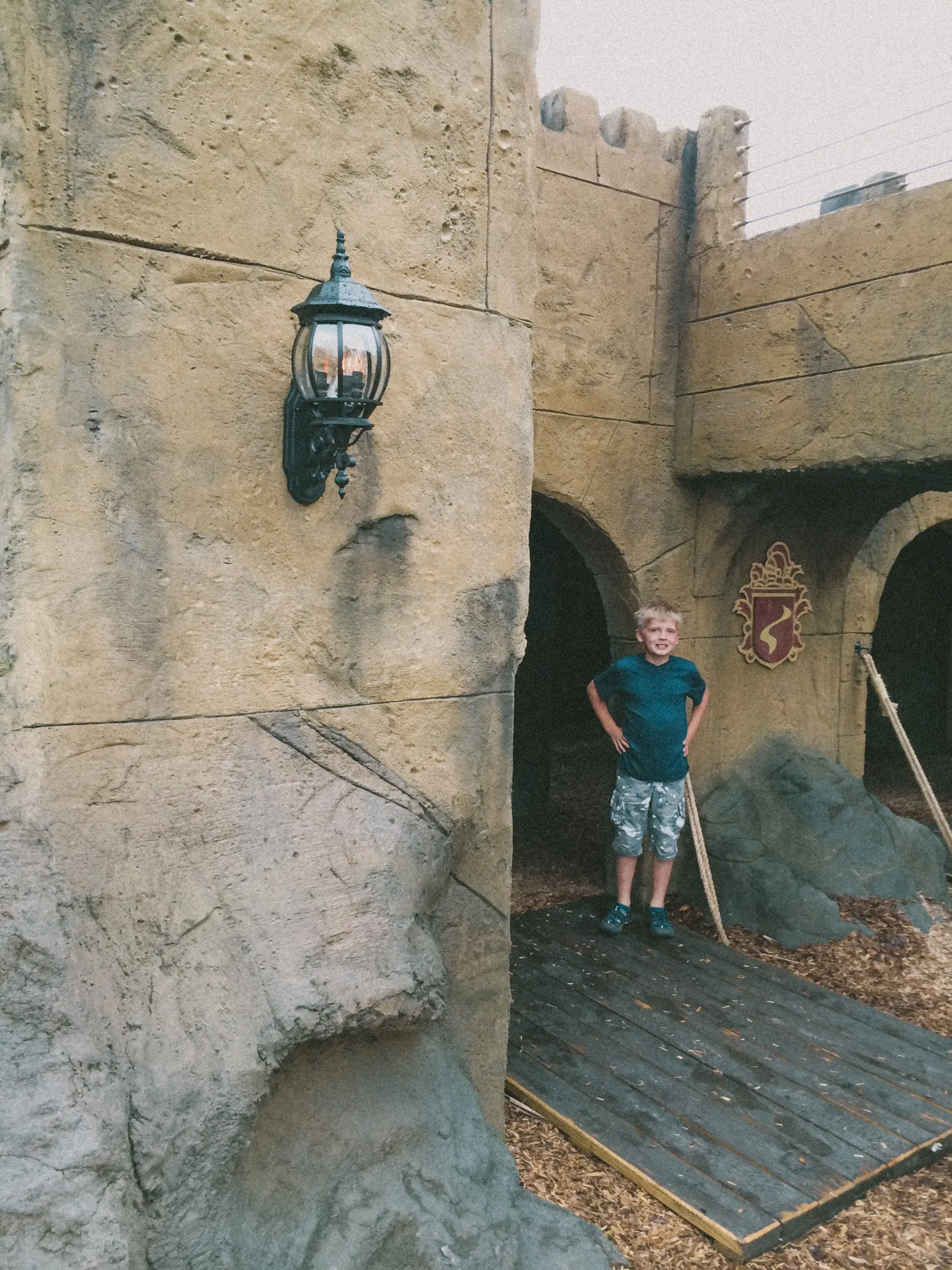 A young boy is standing in front of a castle.