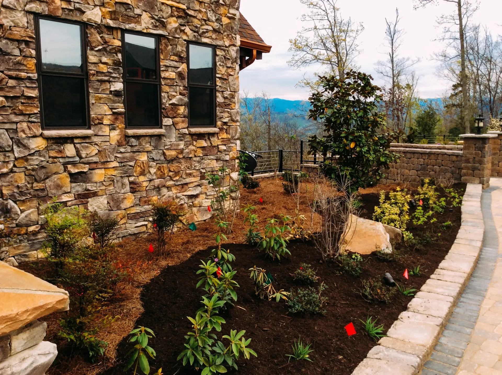 A stone house with a lush green garden in front of it.
