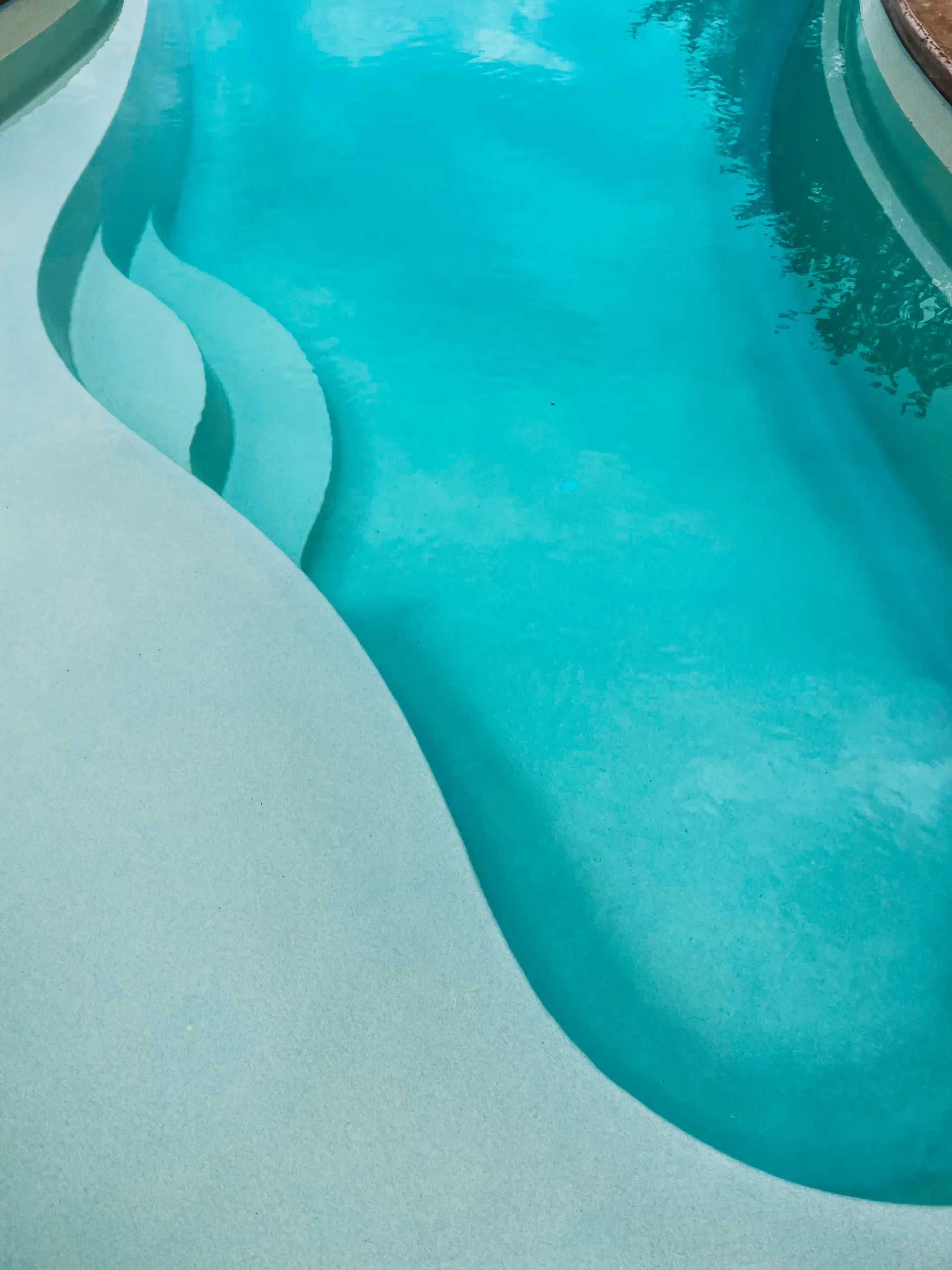 A swimming pool with blue water and a white staircase