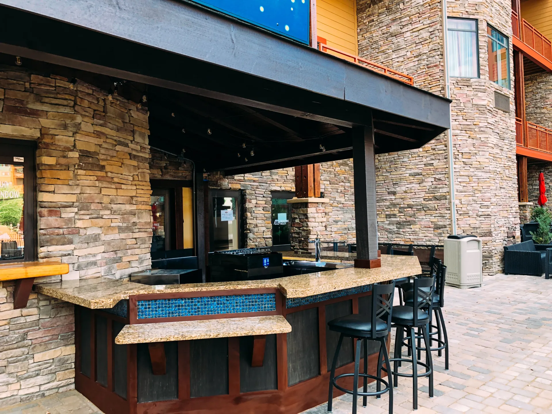 A brick building with a bar and stools in front of it.