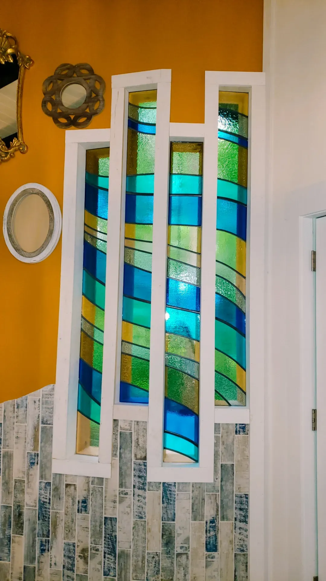 Final stained glass window installation with green, blue, and gold glass