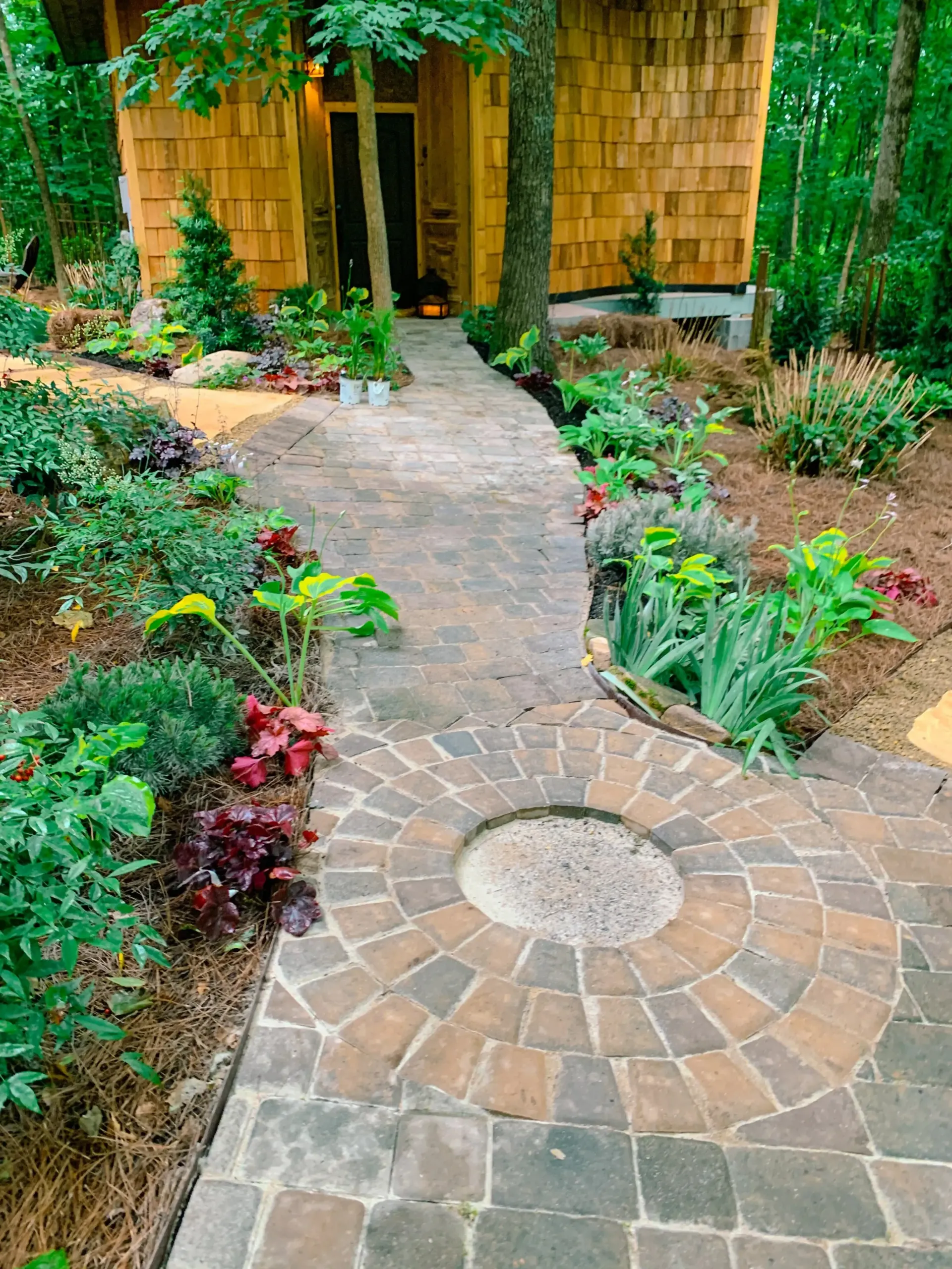 A brick walkway leading to a wooden house in the woods.