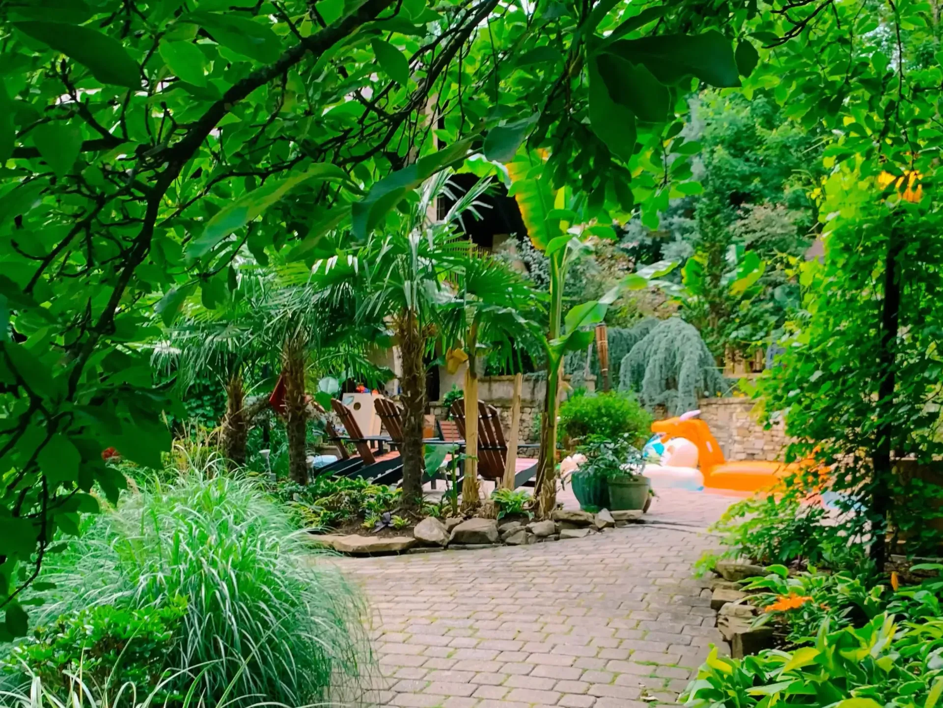 A brick walkway leading to a pool surrounded by trees
