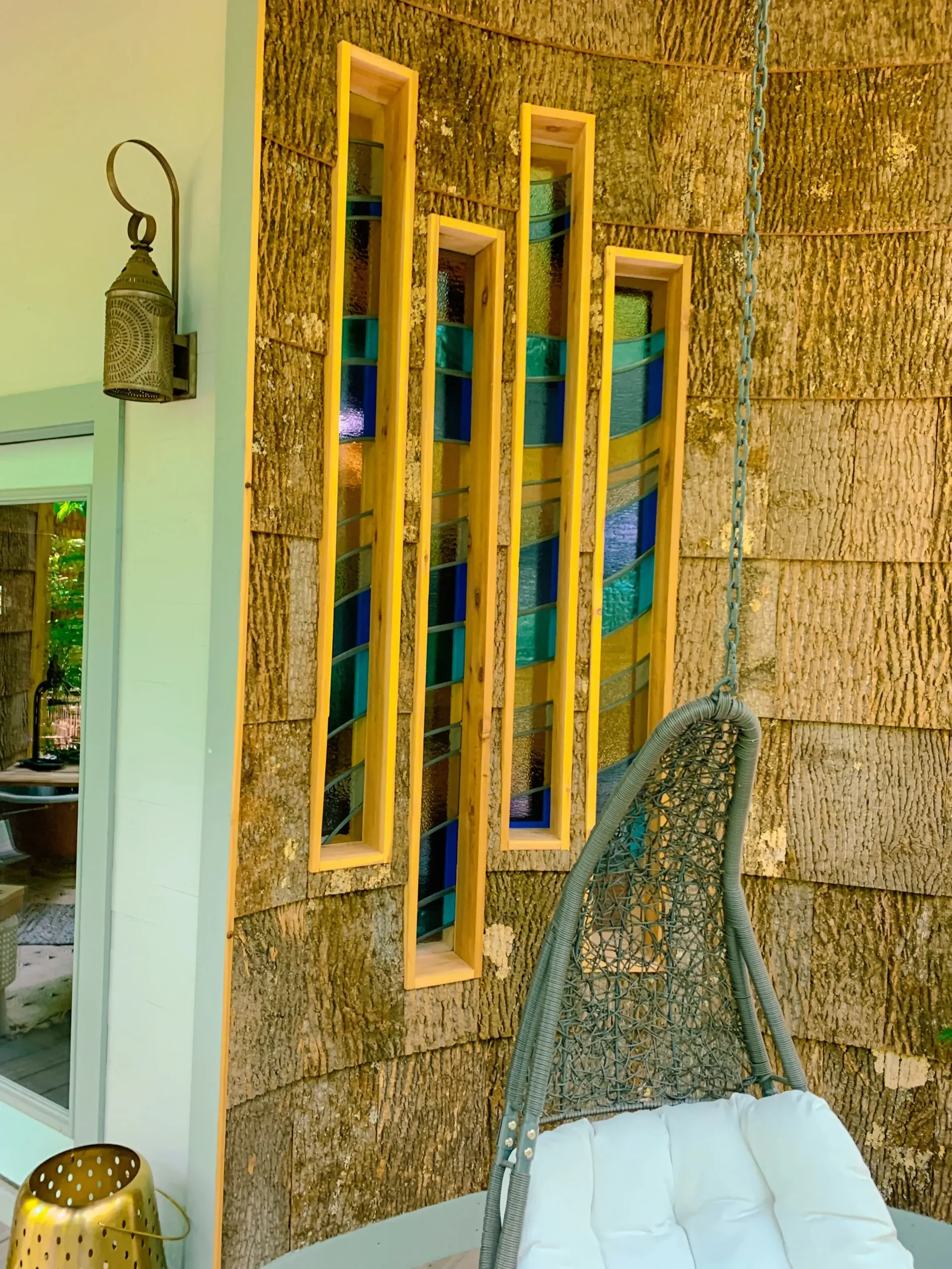 Stained glass feature and porch swing seating area outside custom she shed