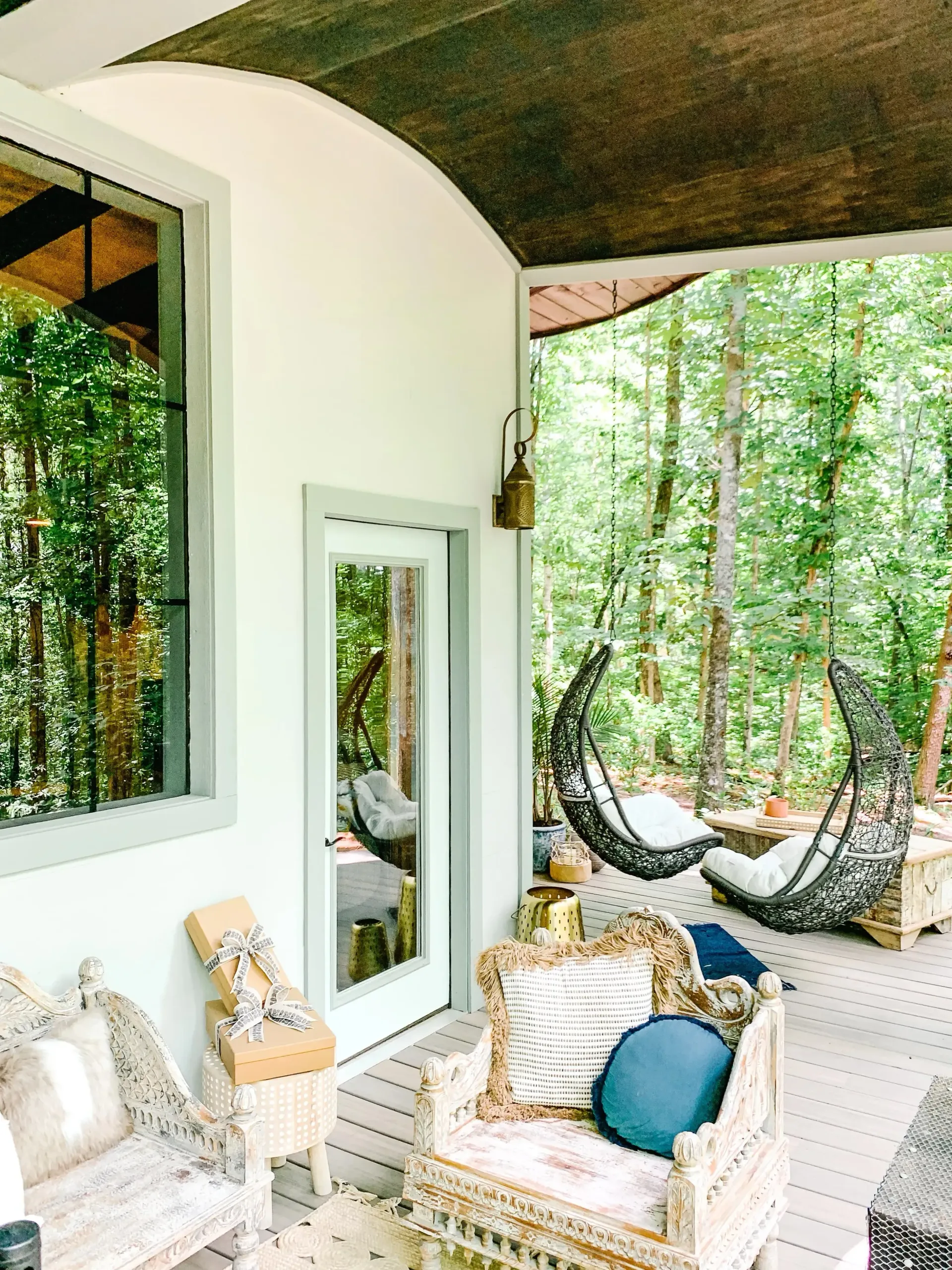 A porch with chairs , a hammock and a window.