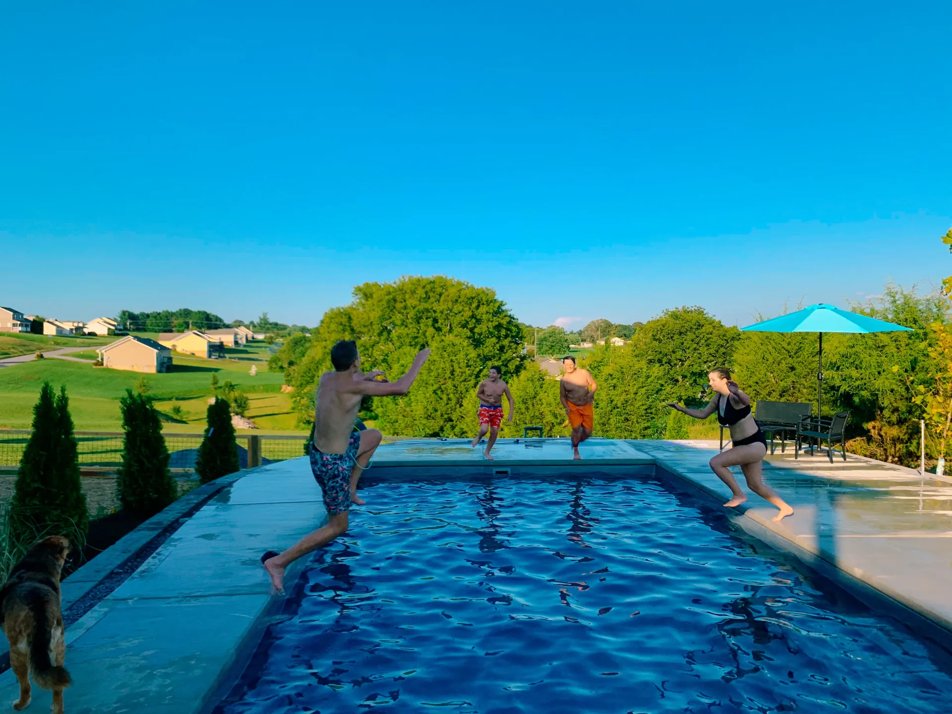 A group of people are jumping into a swimming pool.