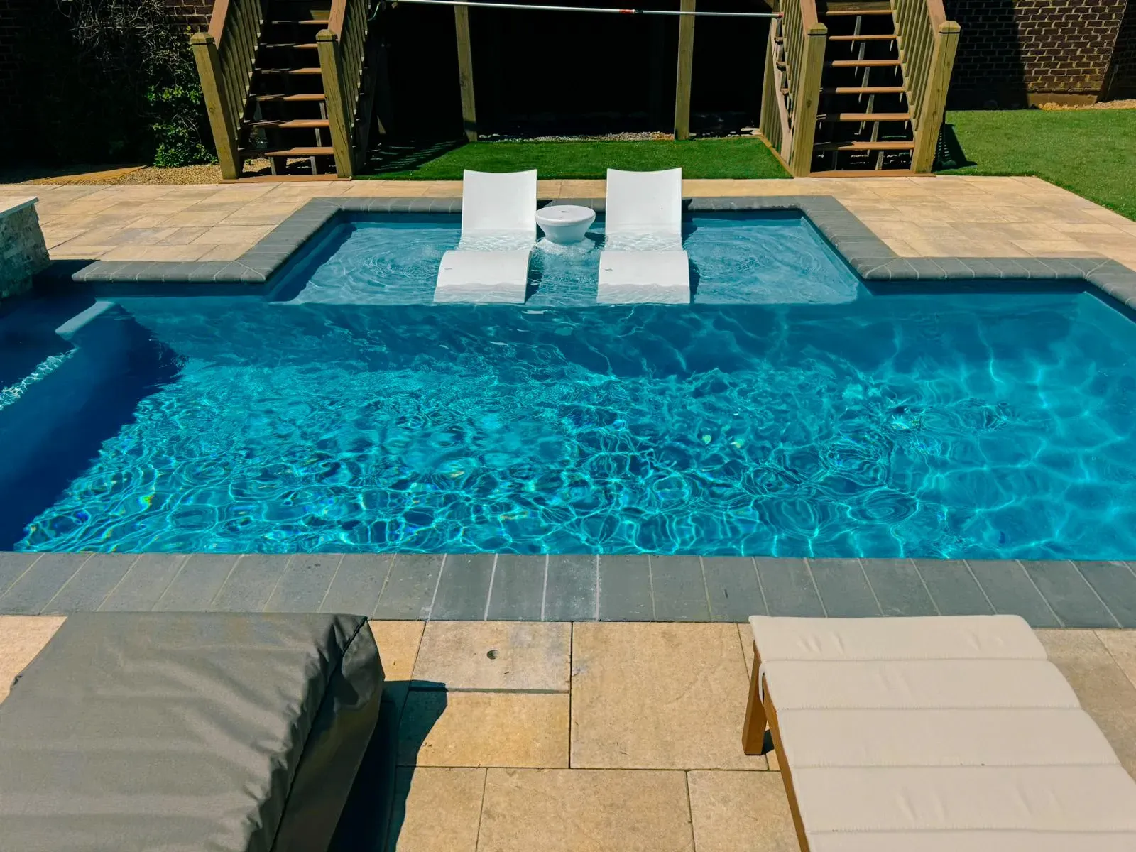 A large swimming pool with two chairs in it