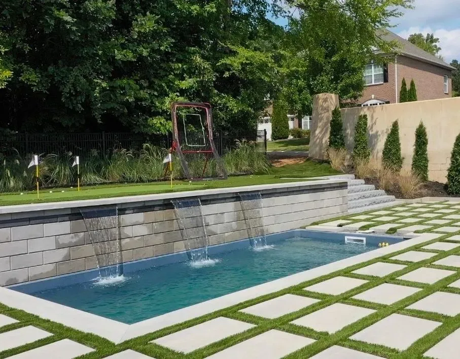 A large swimming pool with a waterfall in the backyard.