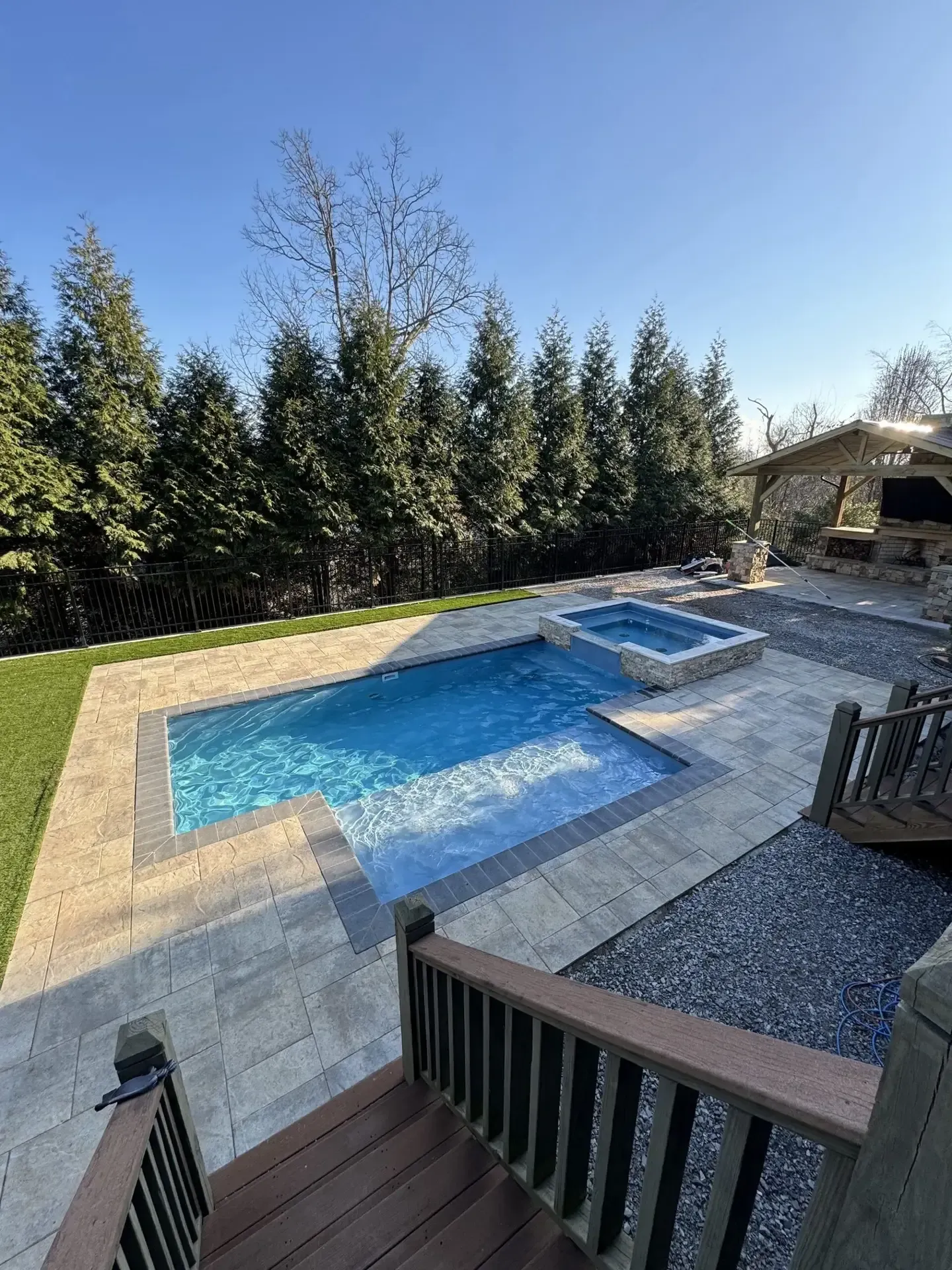 There is a large swimming pool and a hot tub in the backyard.