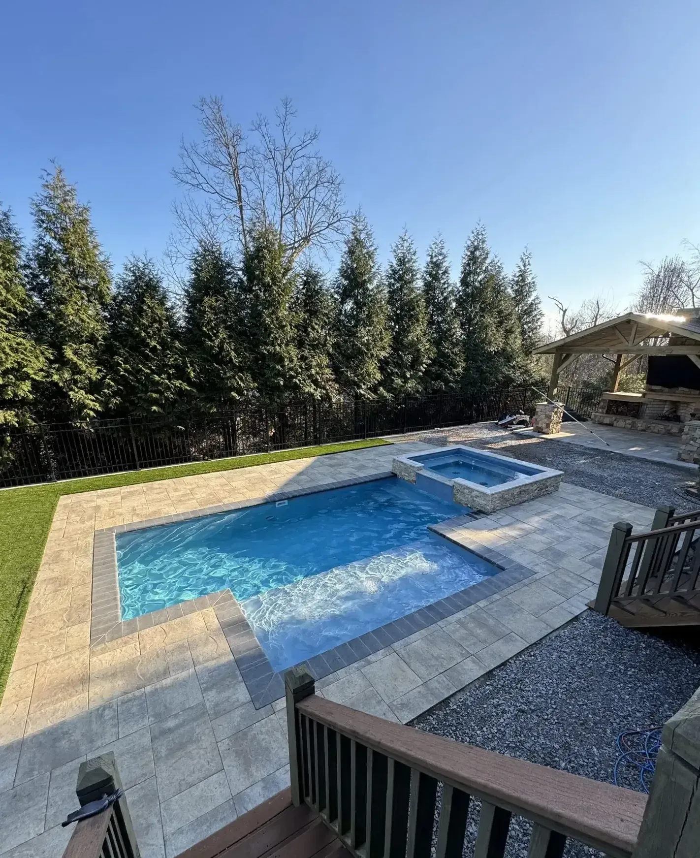 There is a large swimming pool and a hot tub in the backyard.