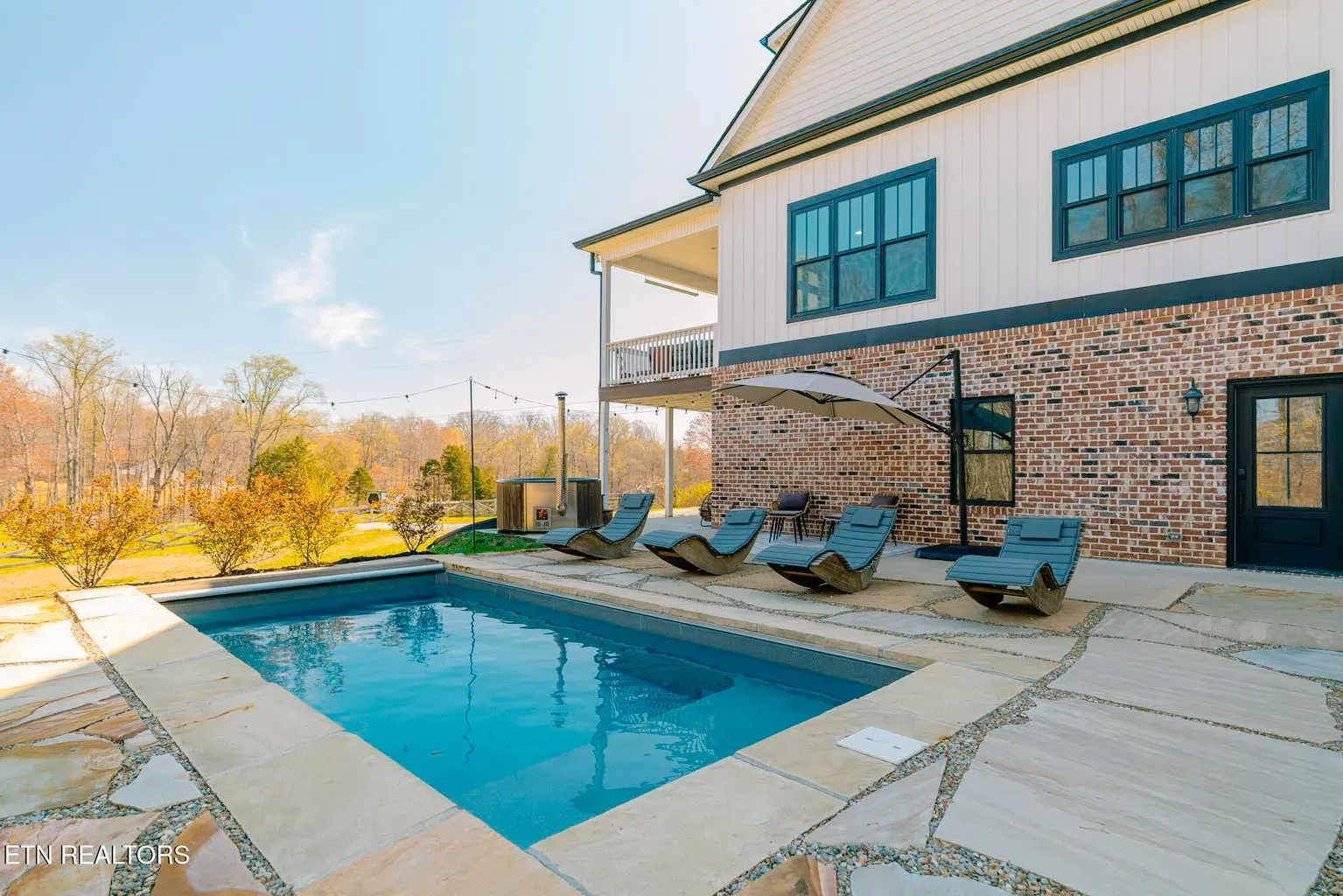 There is a large swimming pool in the backyard of a house.