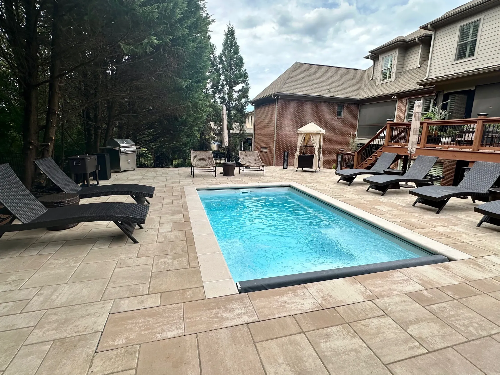 A large swimming pool surrounded by chairs and a house.