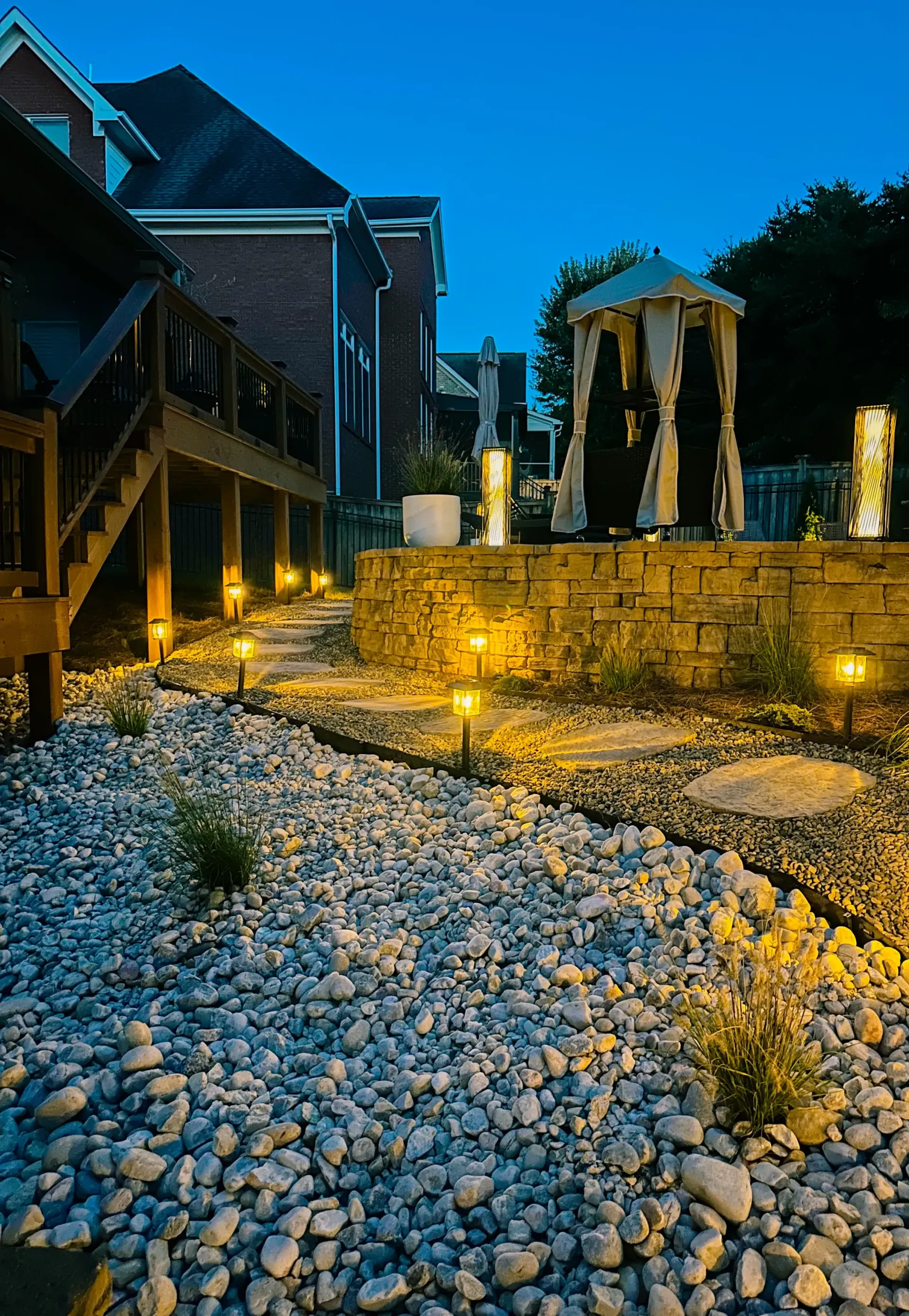 A house with a gazebo in the backyard is lit up at night.