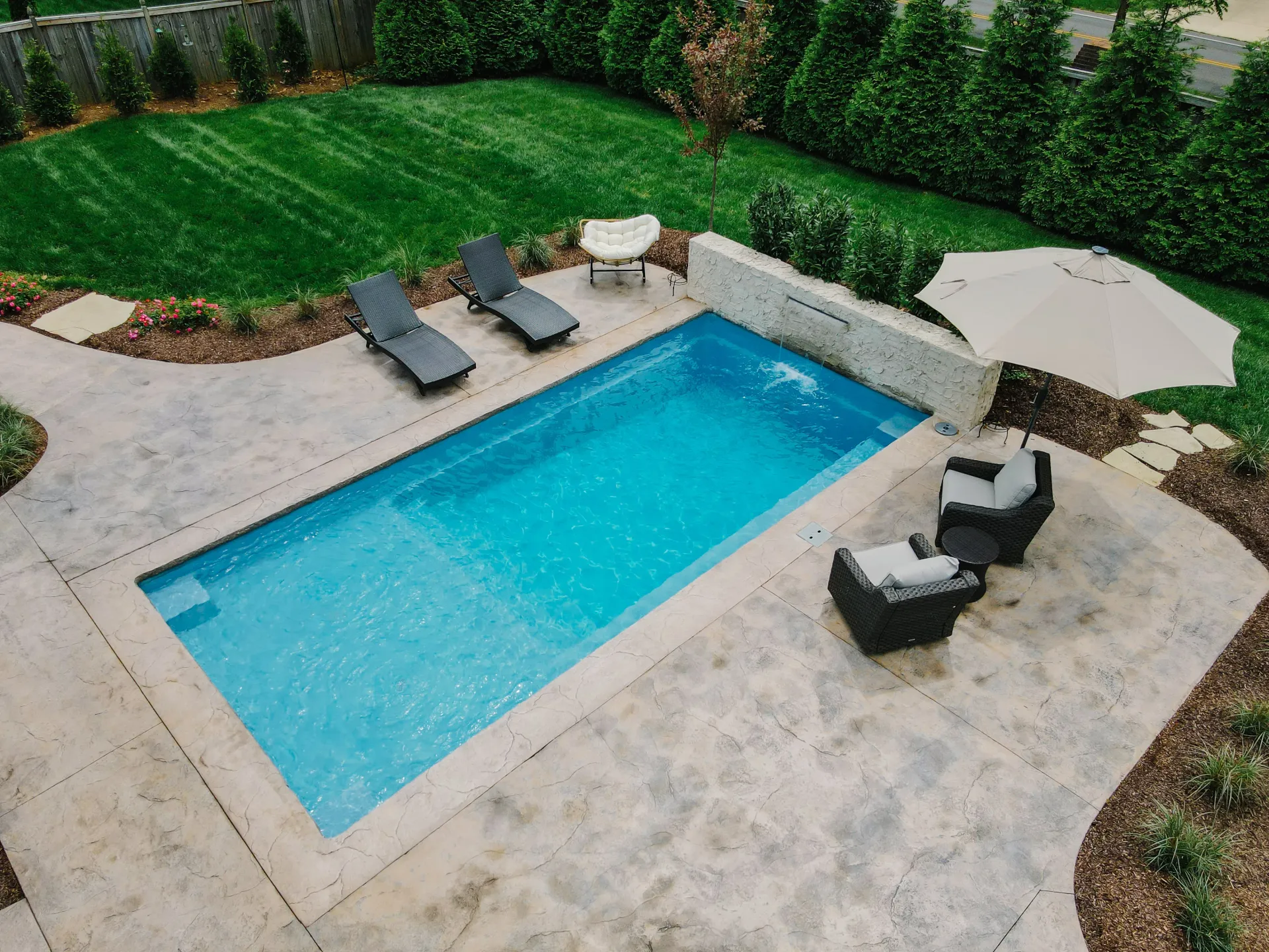 There is a large swimming pool in the backyard of a house.