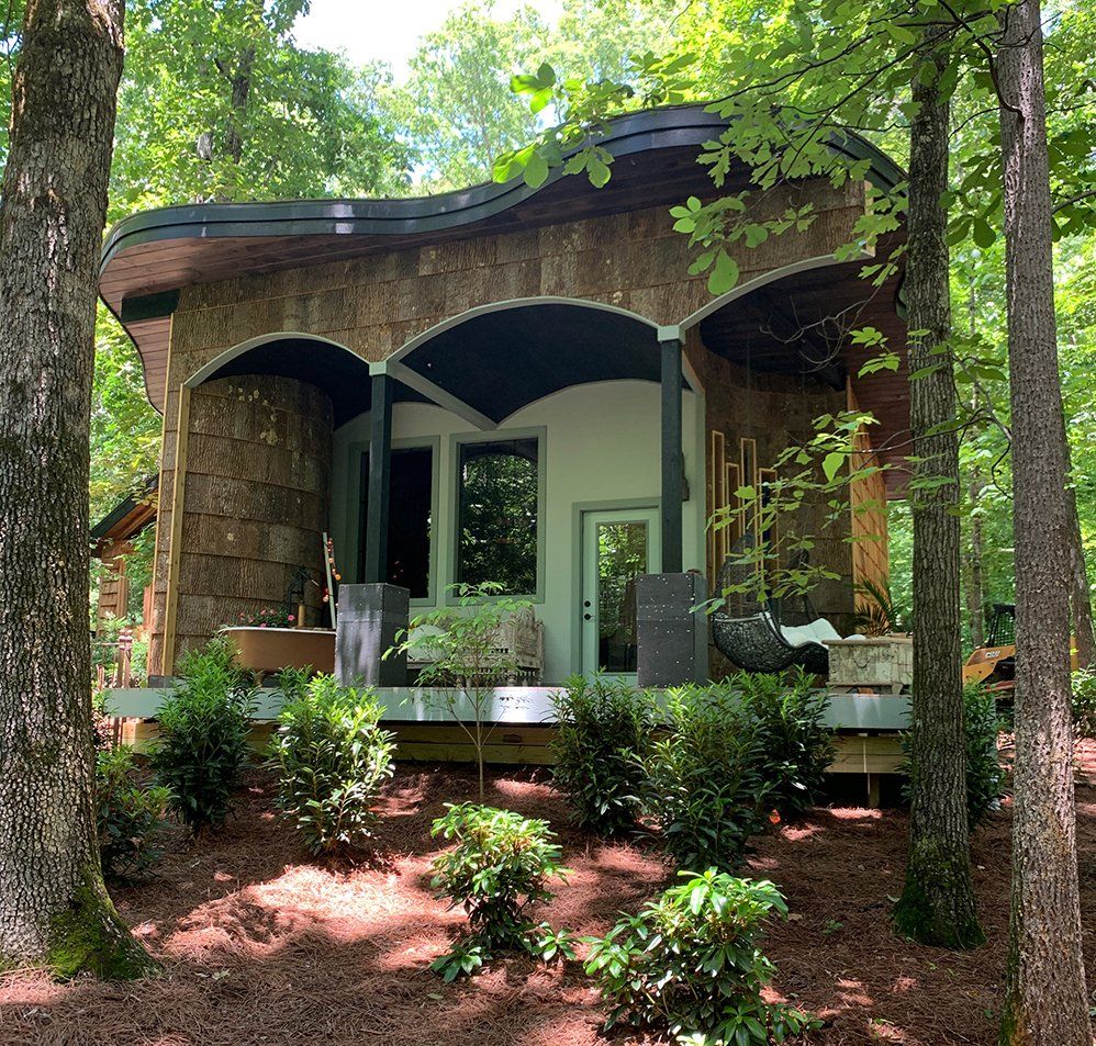 Custom-built luxury she shed with natural materials, curved architecture, and a cozy outdoor retreat feel.