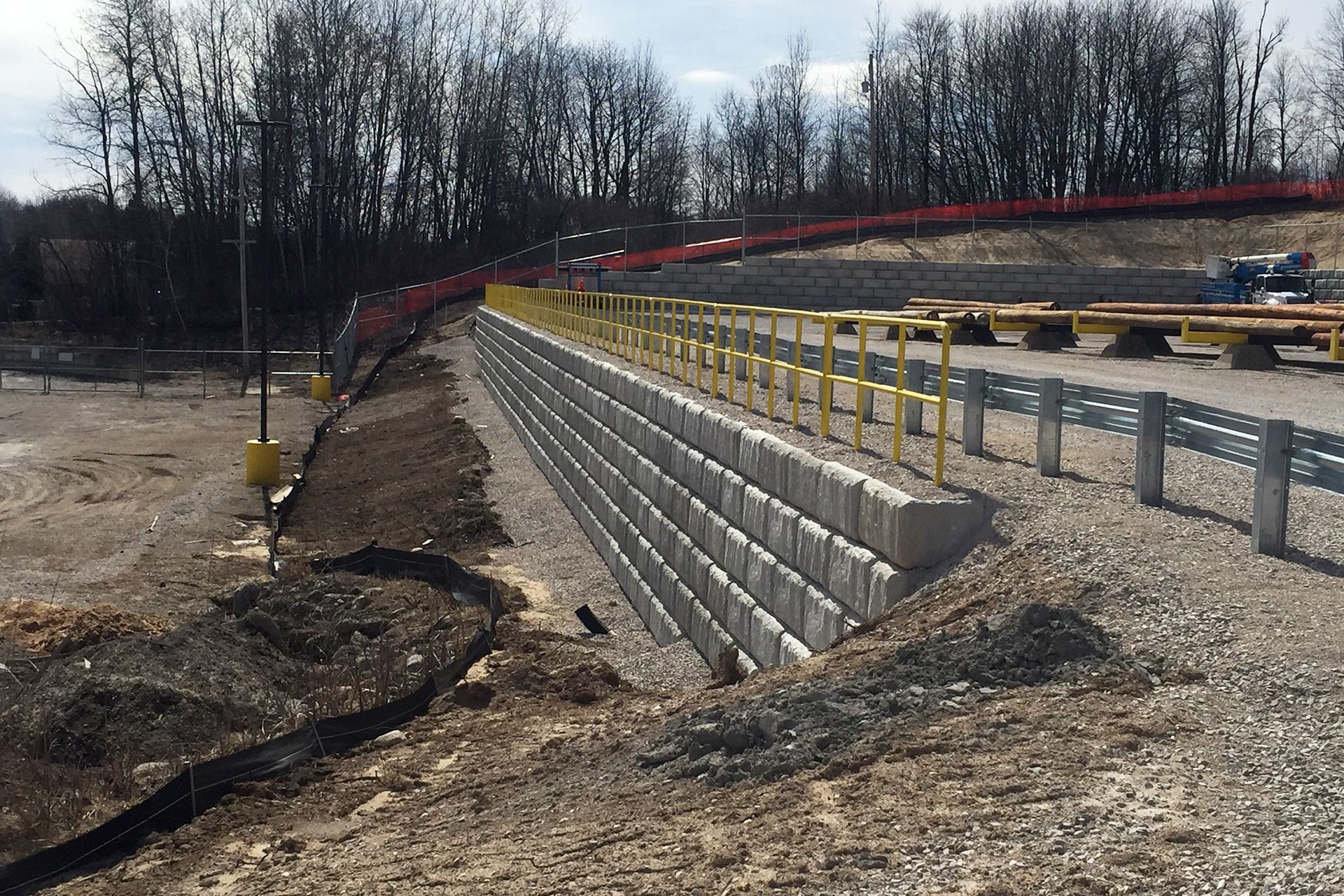 A concrete retaining wall is being built in a dirt field