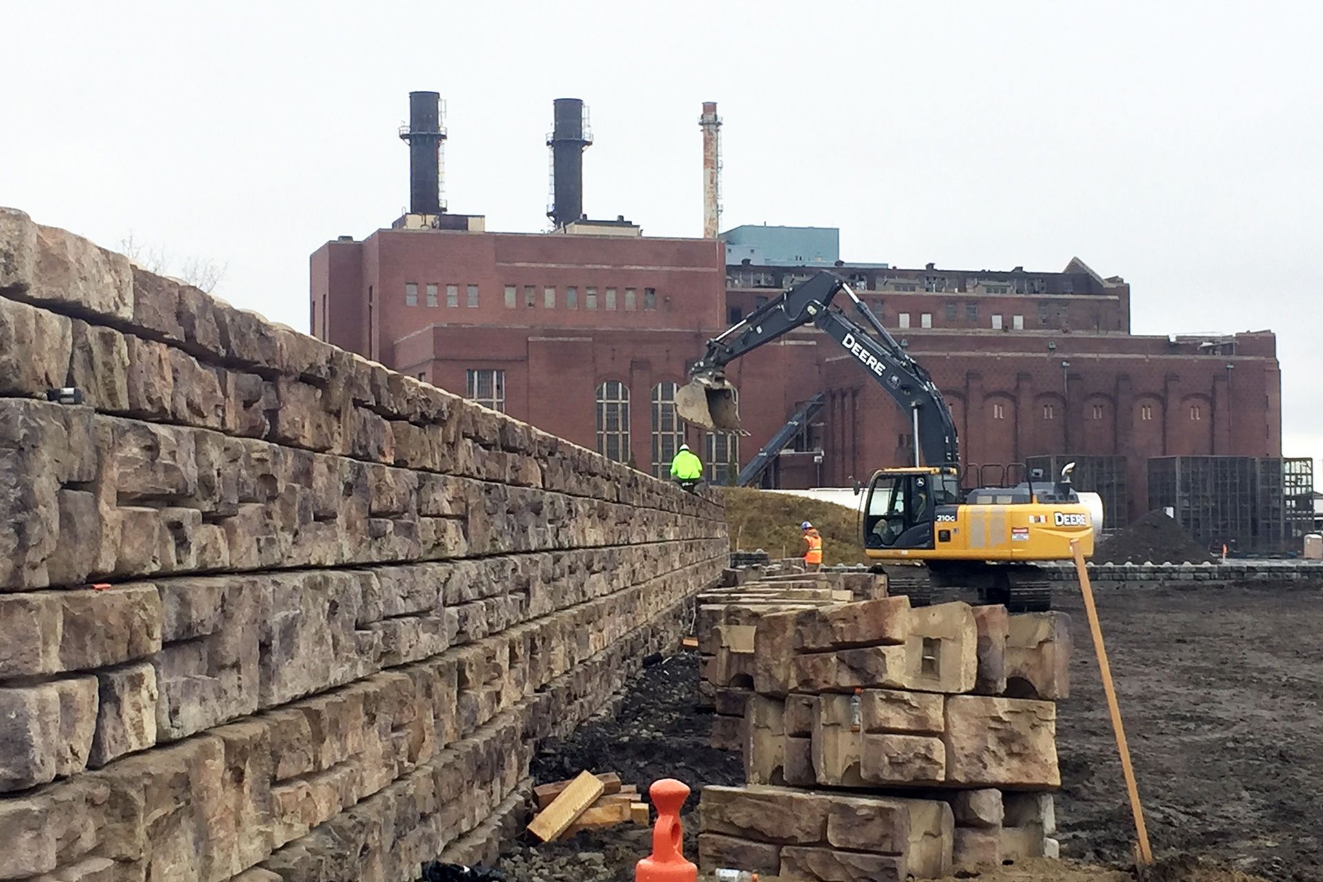 A construction site with a brick wall and a large building in the background.