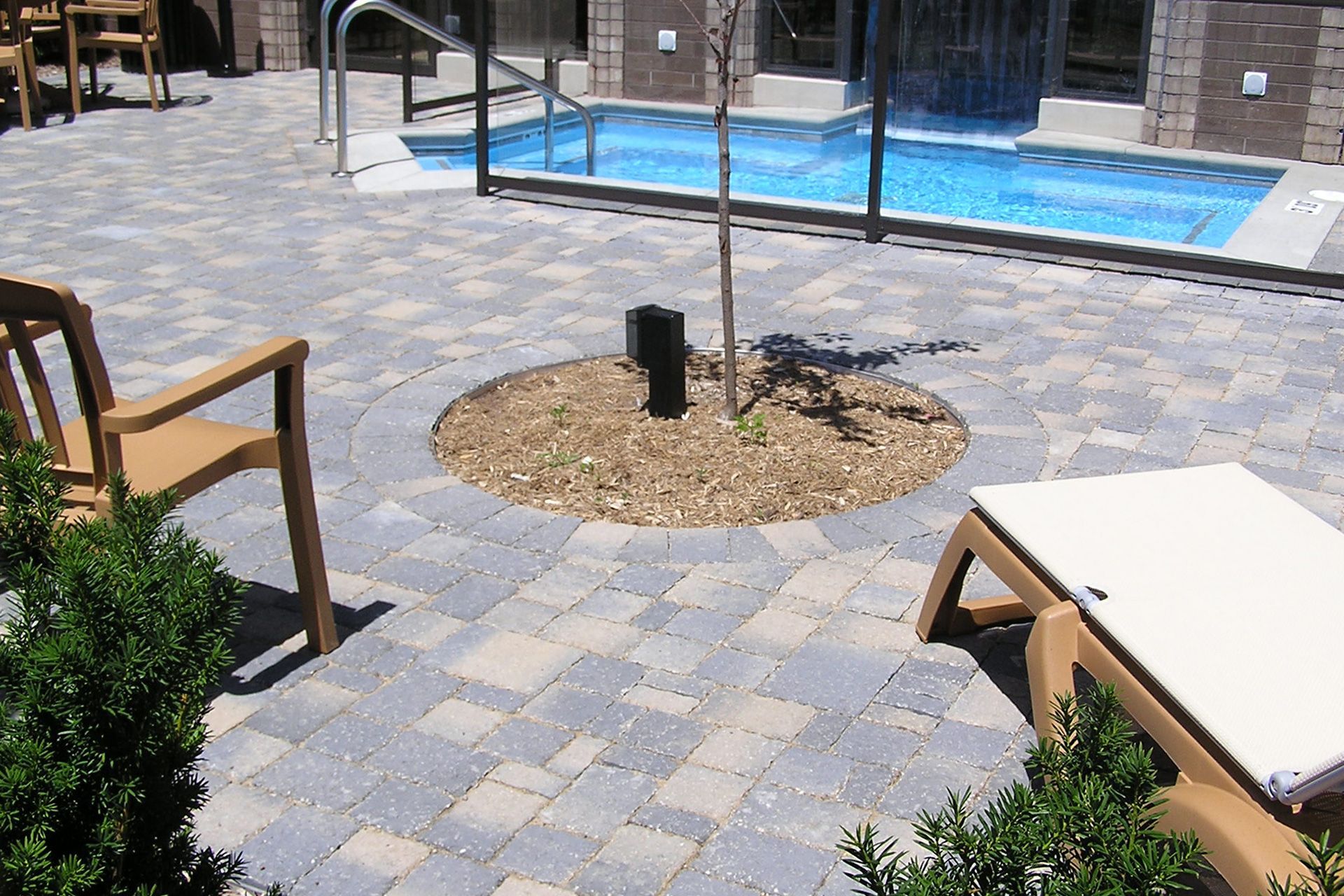 A patio with chairs and a swimming pool in the background