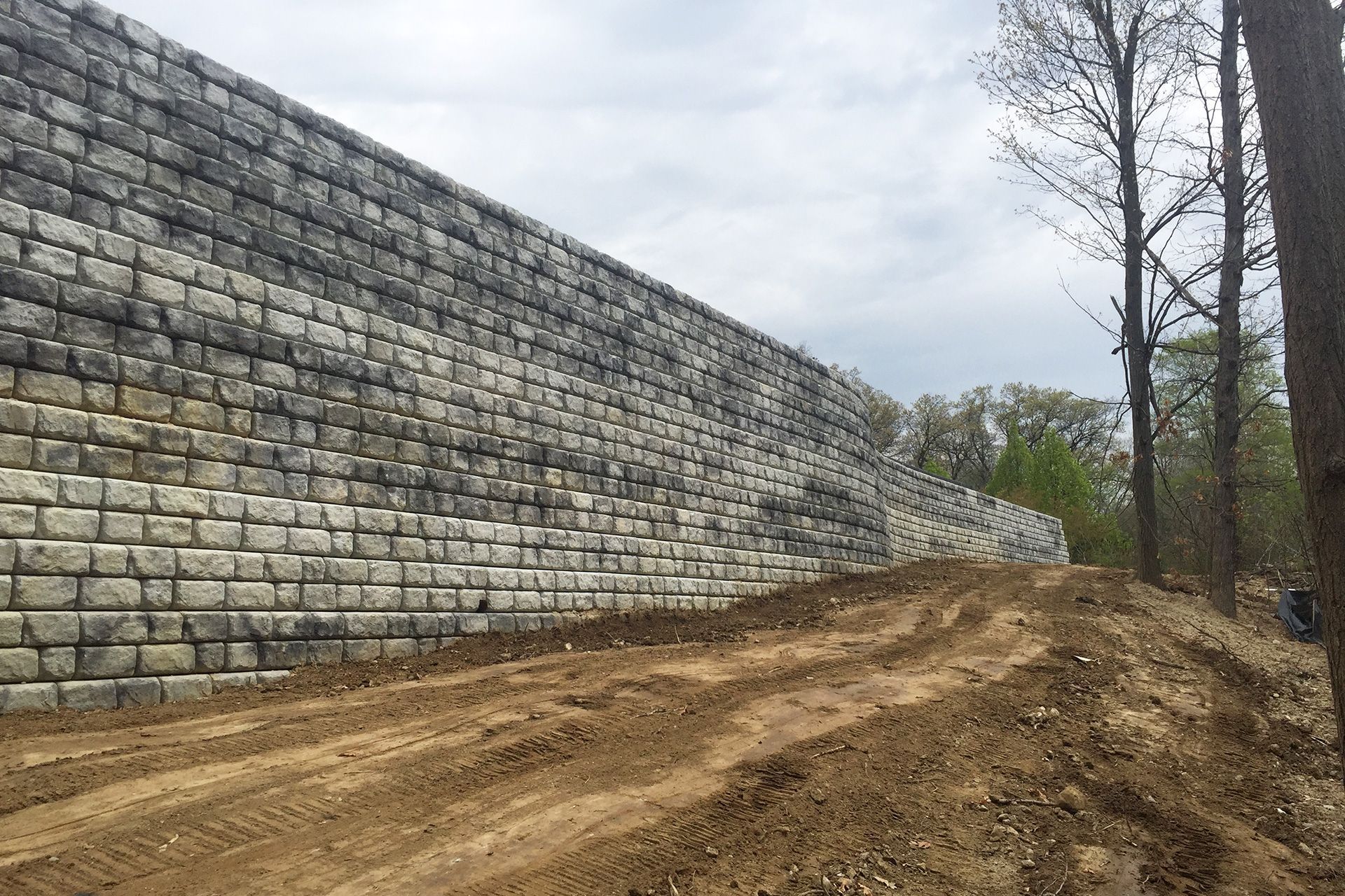A large brick wall is sitting on top of a dirt road.