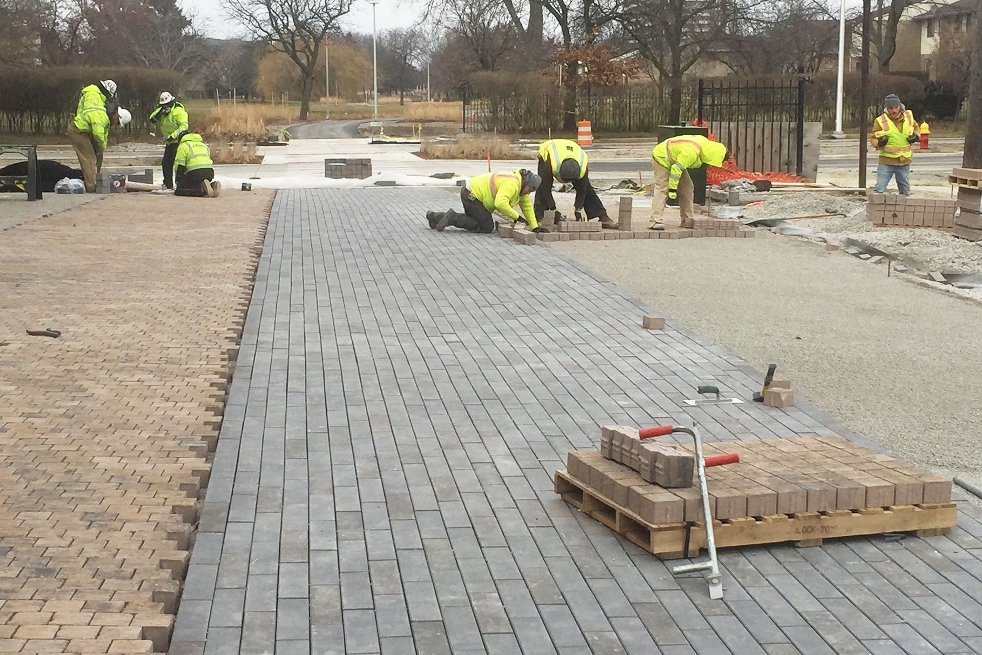 A group of construction workers are working on a brick walkway