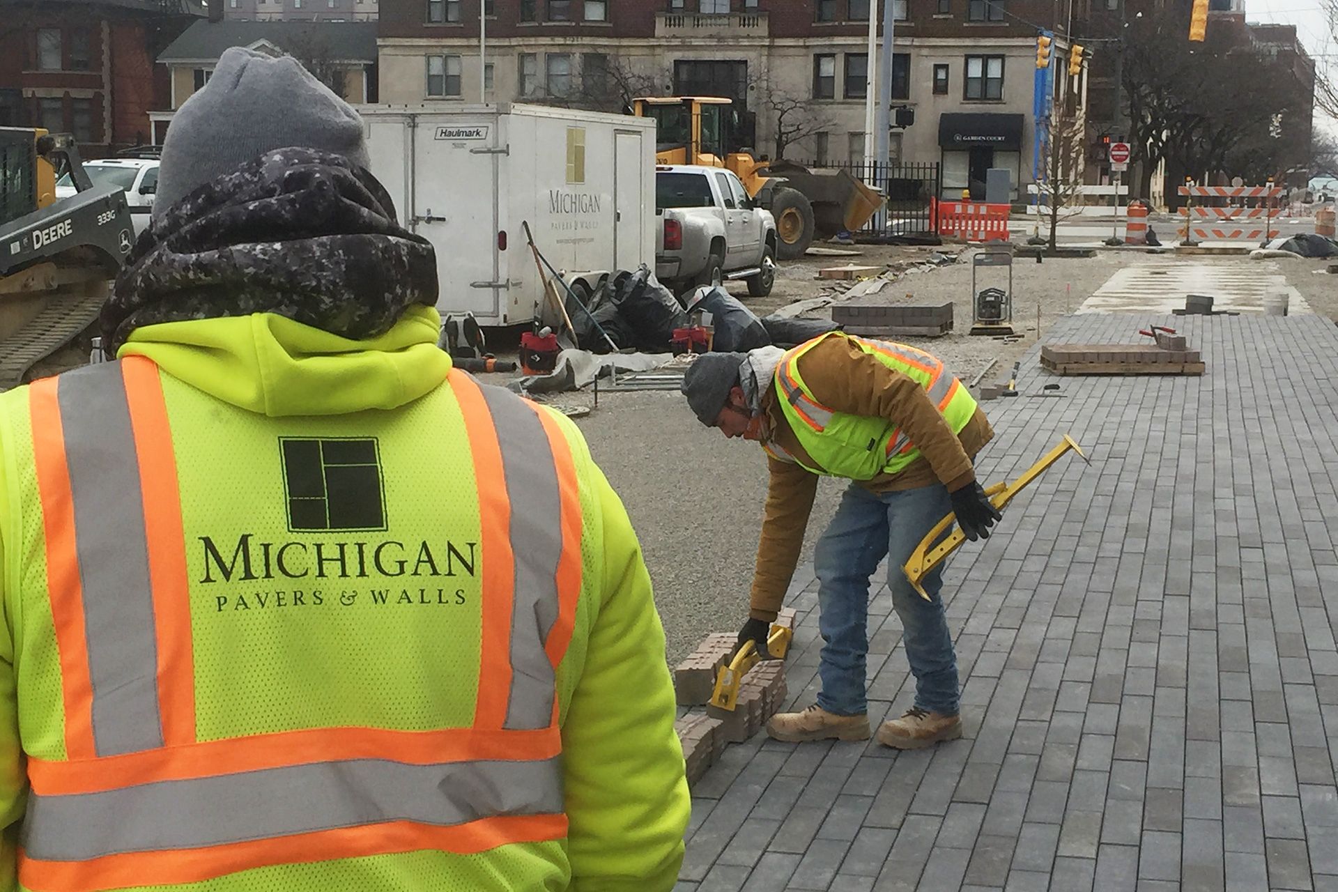 A man wearing a michigan safety vest is working on a sidewalk