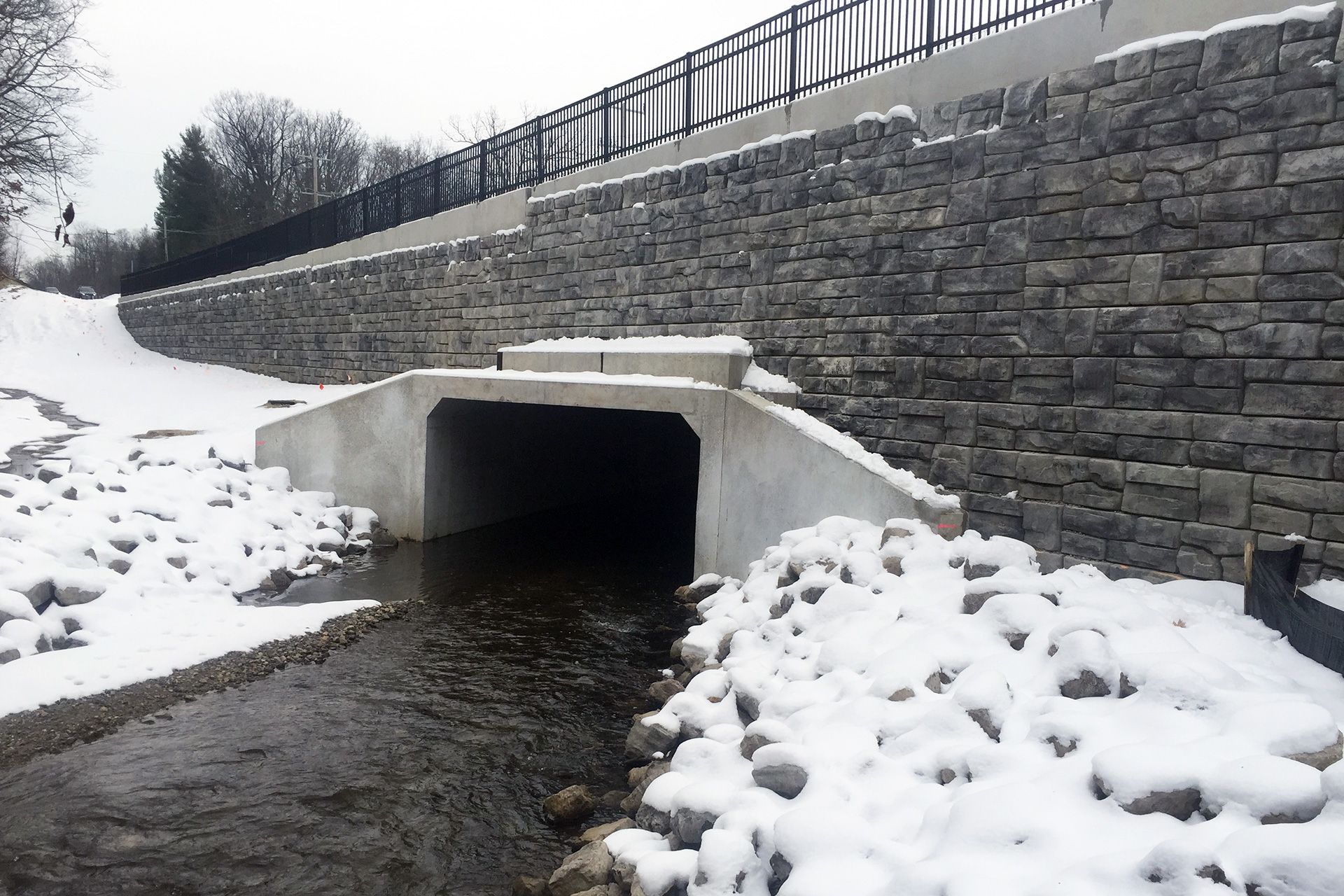 A tunnel leading to a river with snow on the ground
