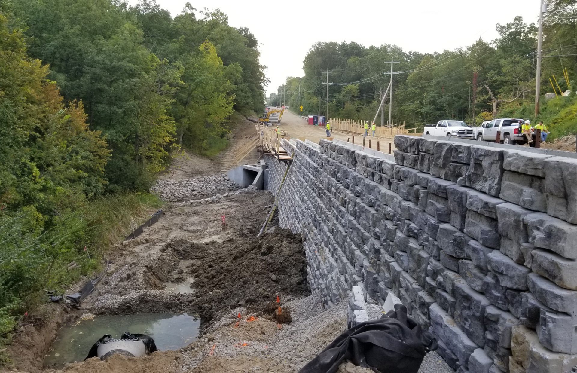 A large stone wall is being built next to a road.