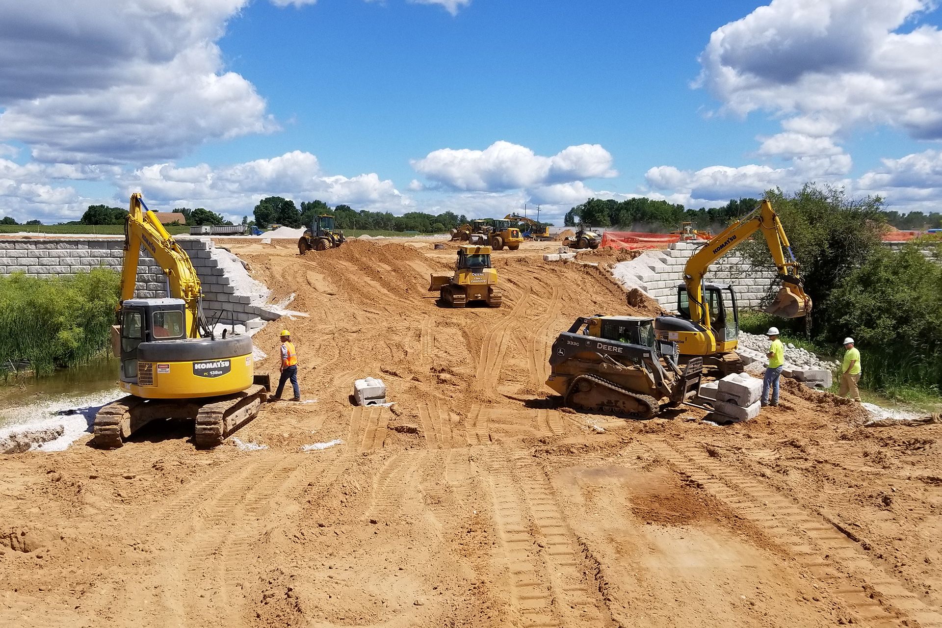 A group of construction vehicles are working on a dirt road.