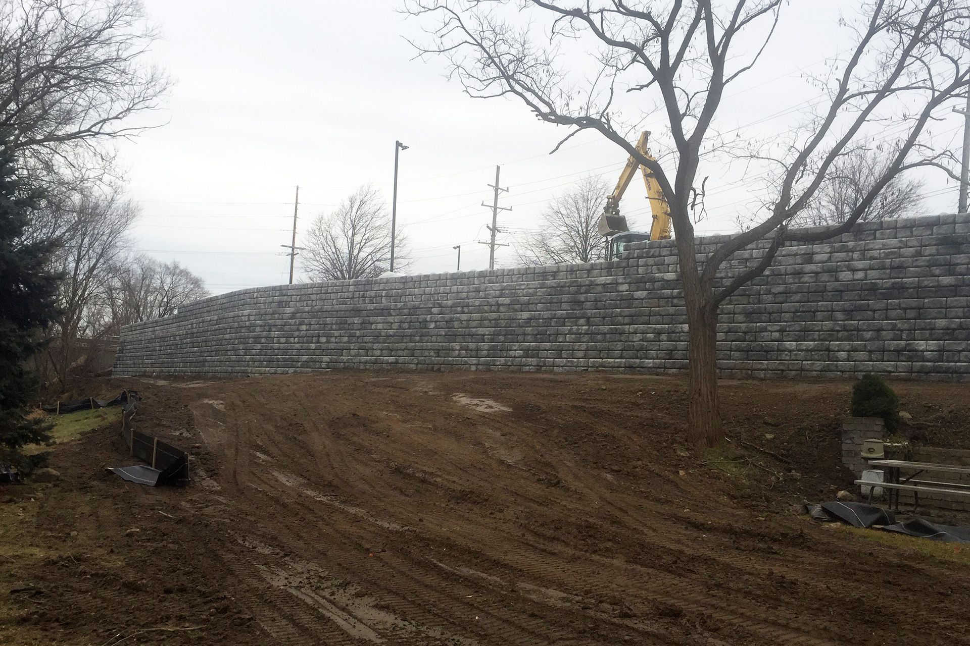 A large stone wall is being built in the middle of a dirt field.