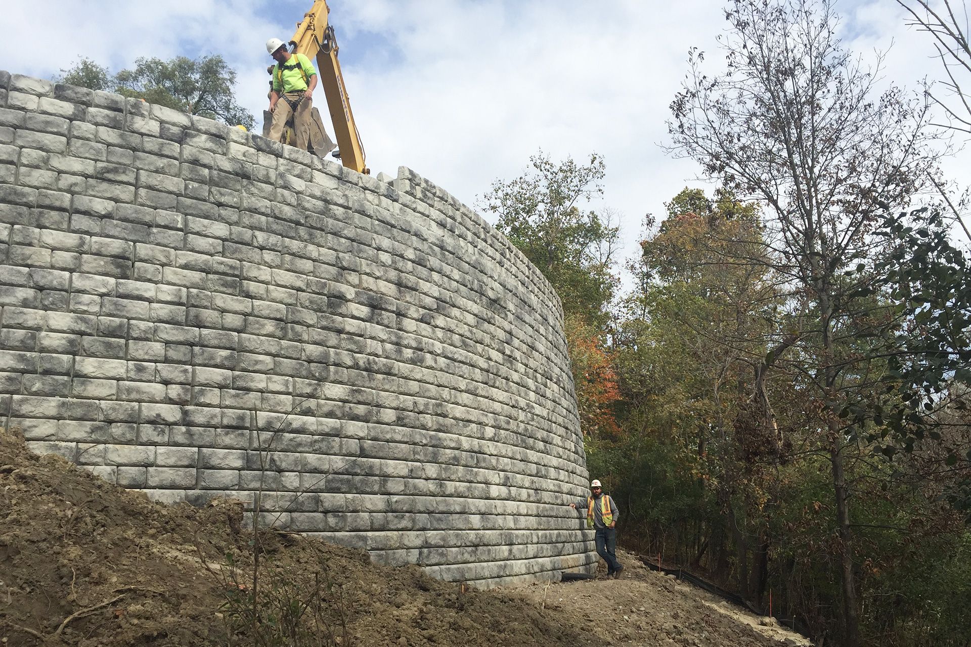 A large brick wall is being built on top of a hill.