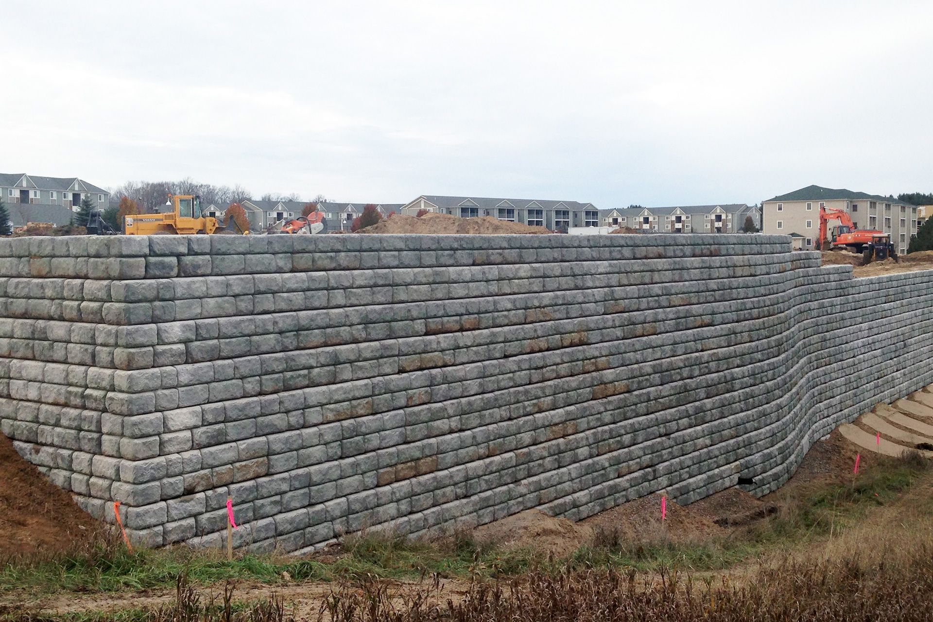 A large brick wall is being built in a field.