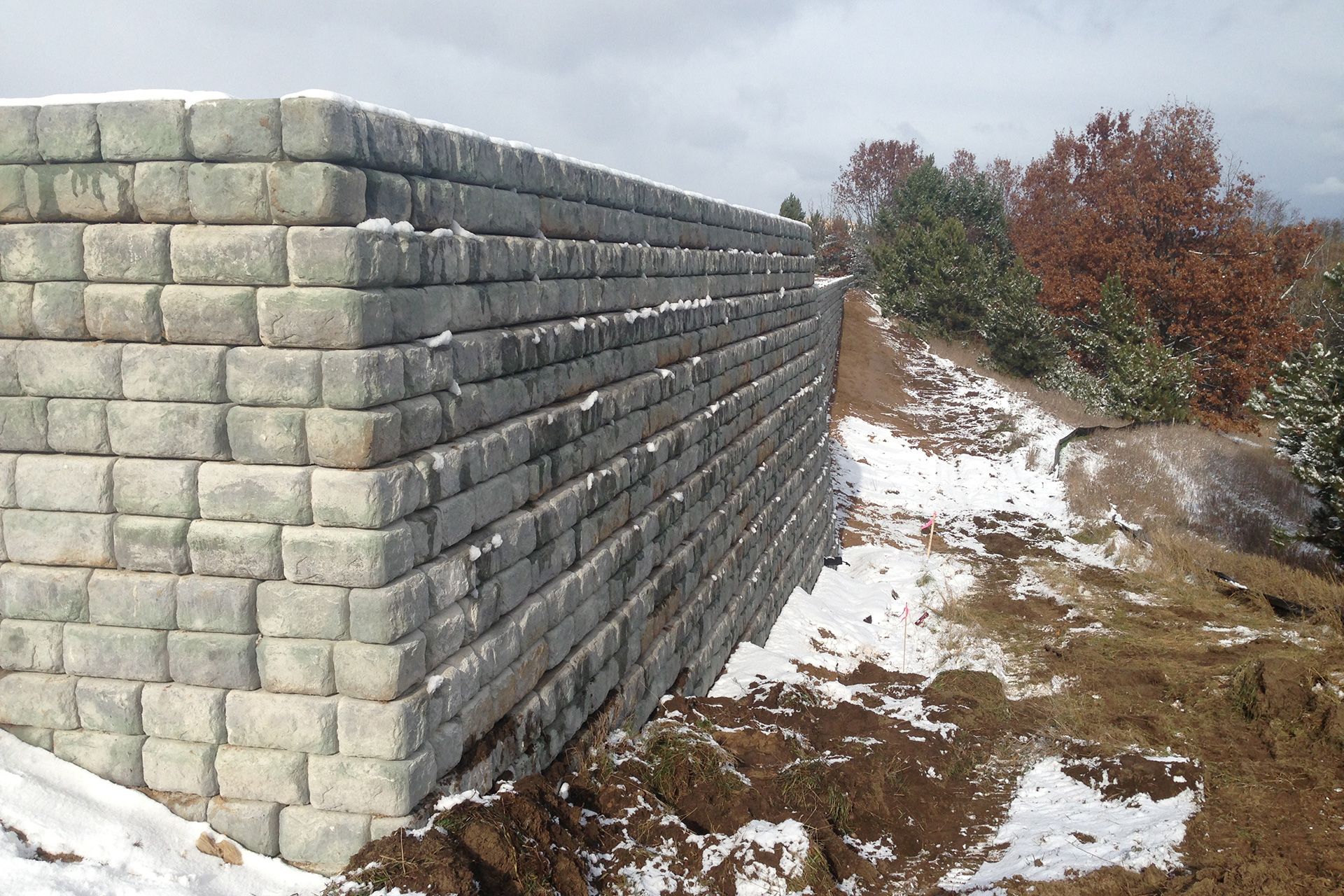 A large brick wall is surrounded by snow and dirt.