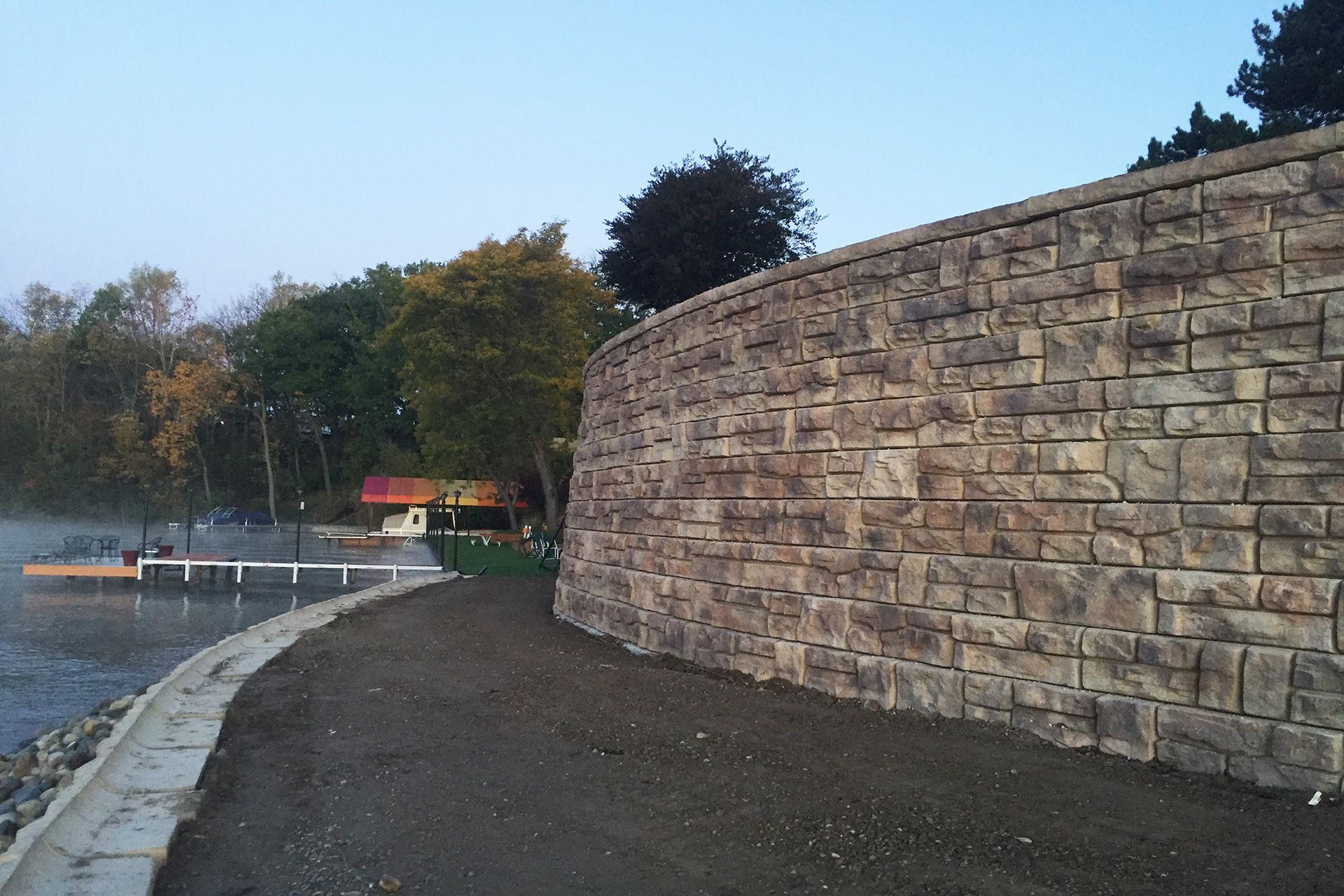 A large stone wall along the shore of a lake