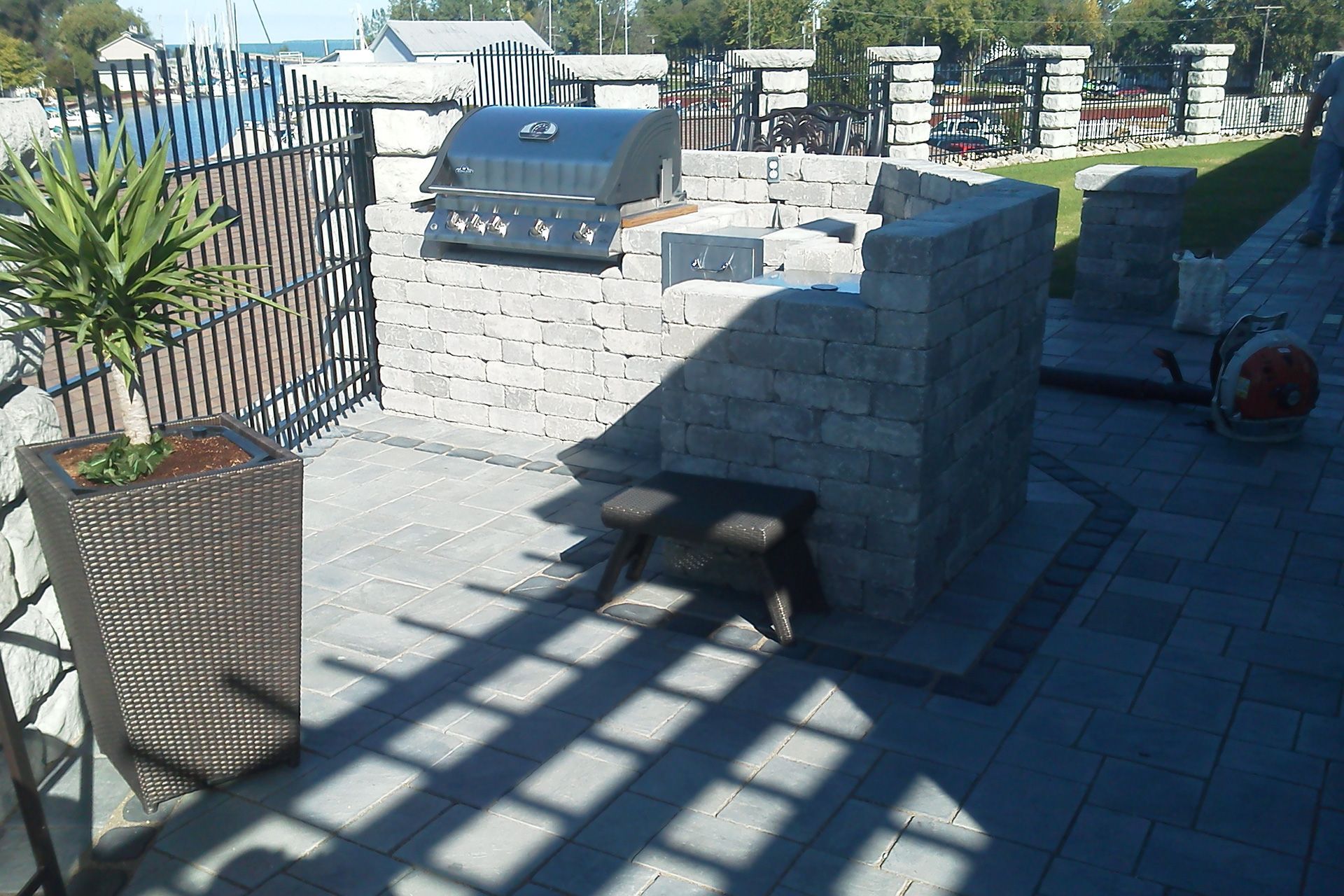A patio with a grill and a planter with a plant in it