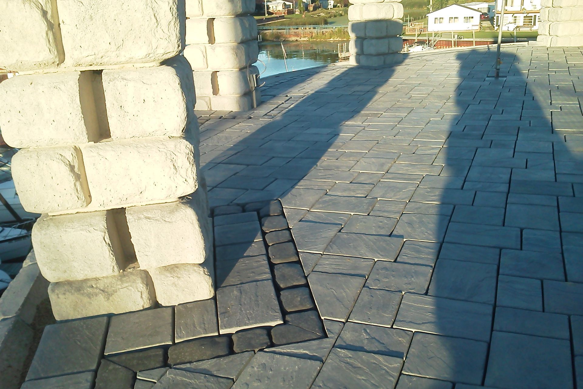 A brick walkway with a shadow of a person on it