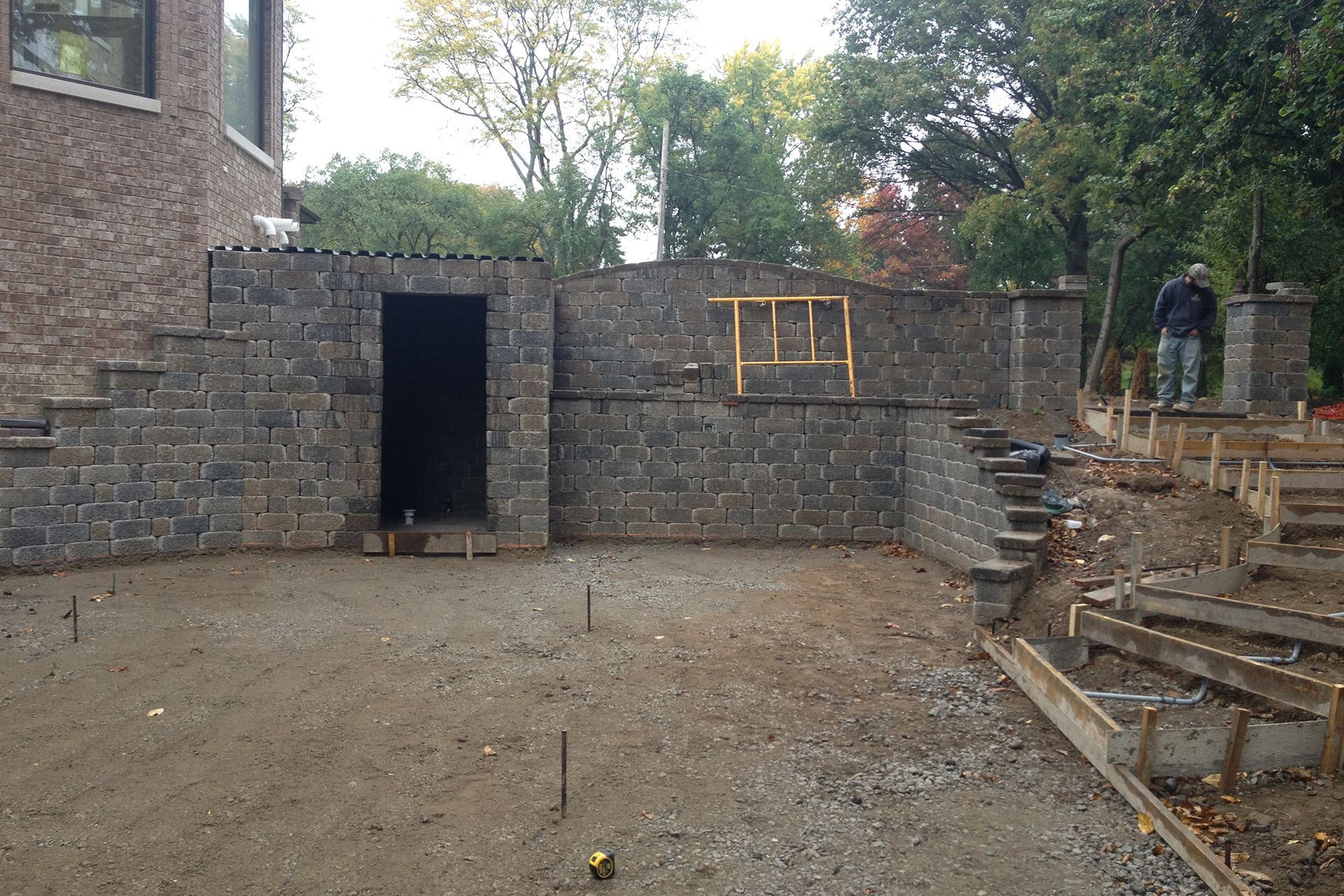 A brick wall is being built in the backyard of a house