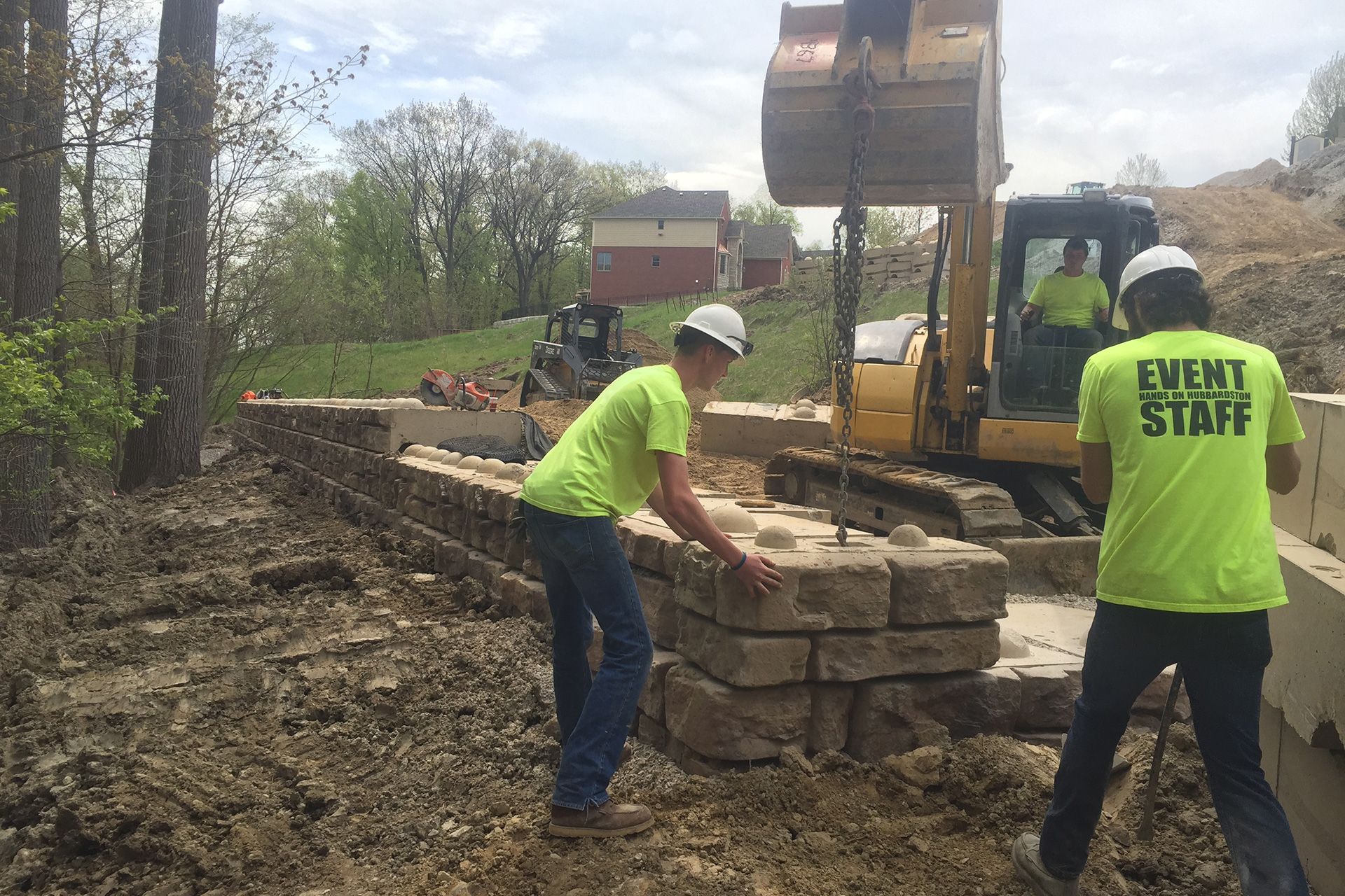 Two men wearing neon green shirts that say event staff are working on a construction site.
