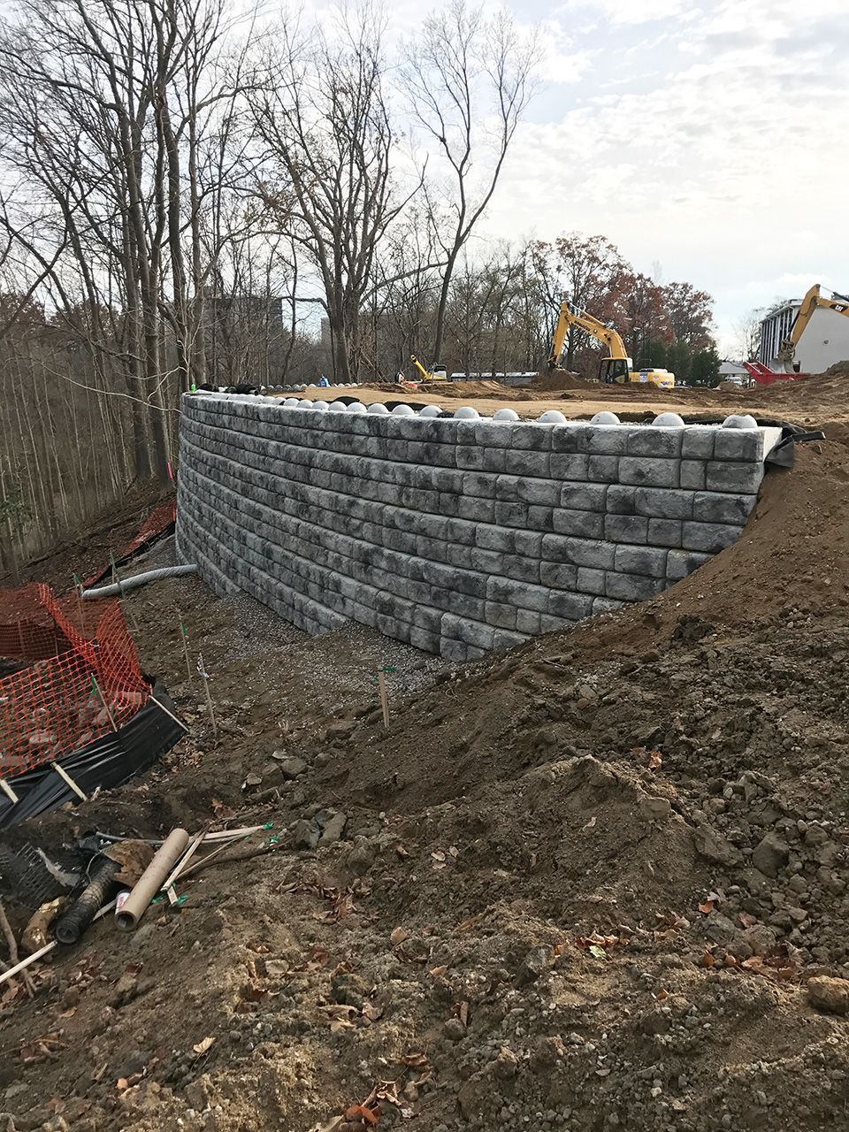 A large brick wall is being built in the middle of a dirt field.