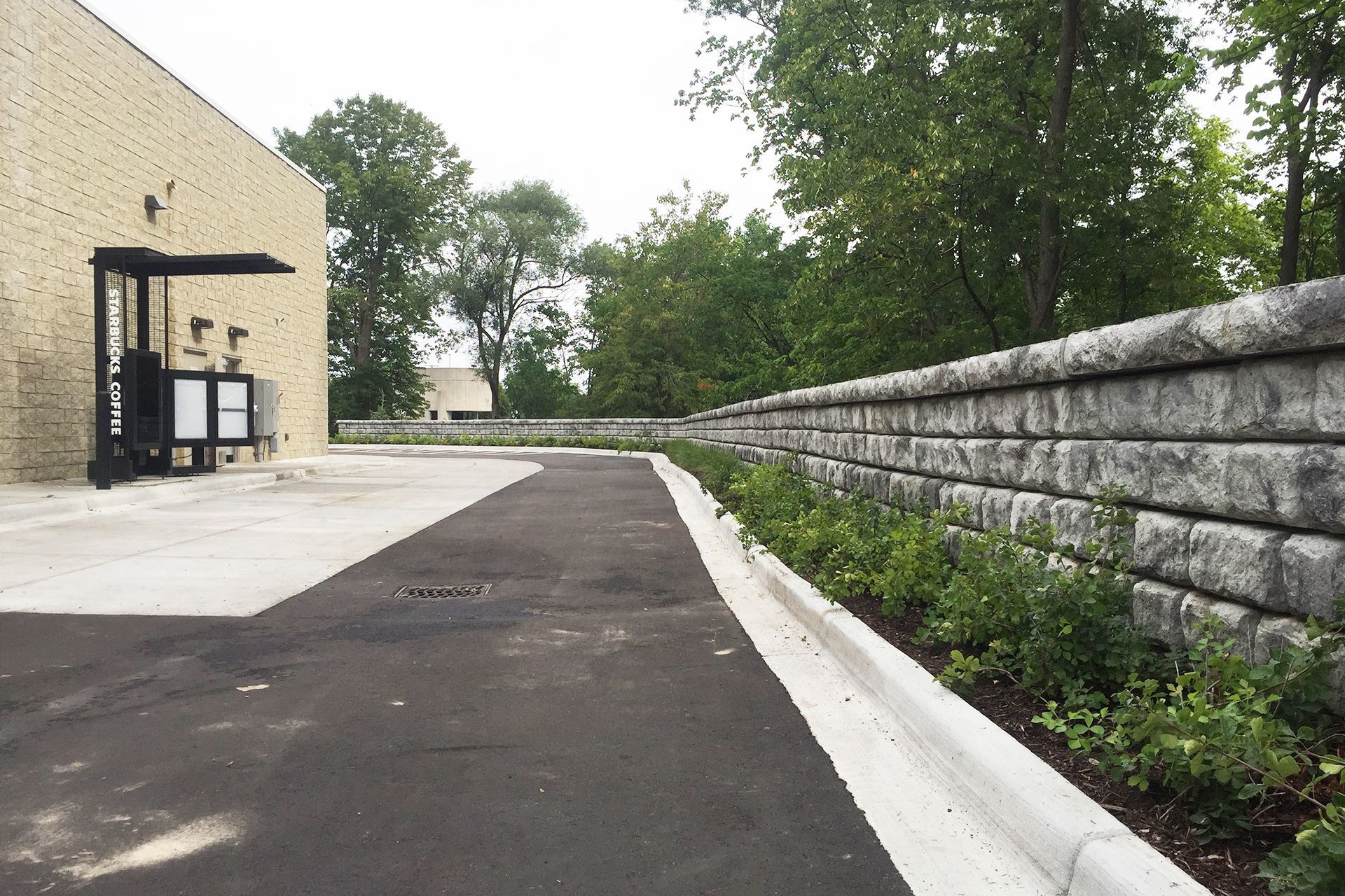 A brick wall along the side of a road in front of a building