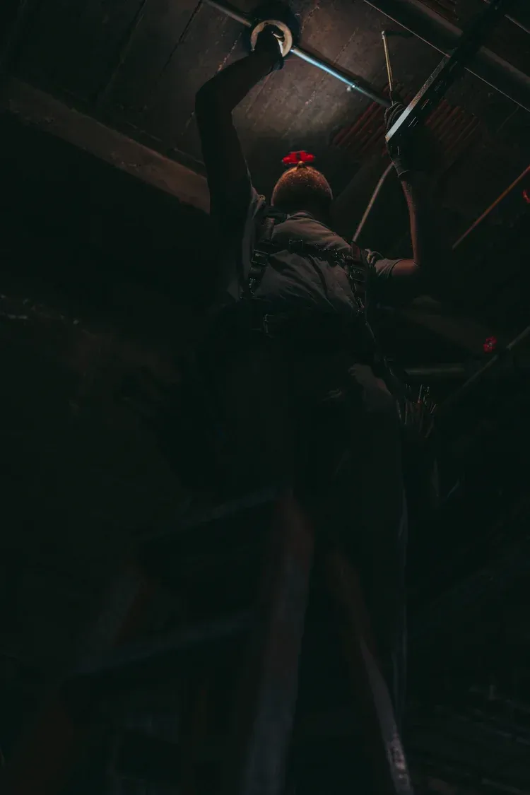 Person hanging upside down, chains, dimly lit interior, dark.