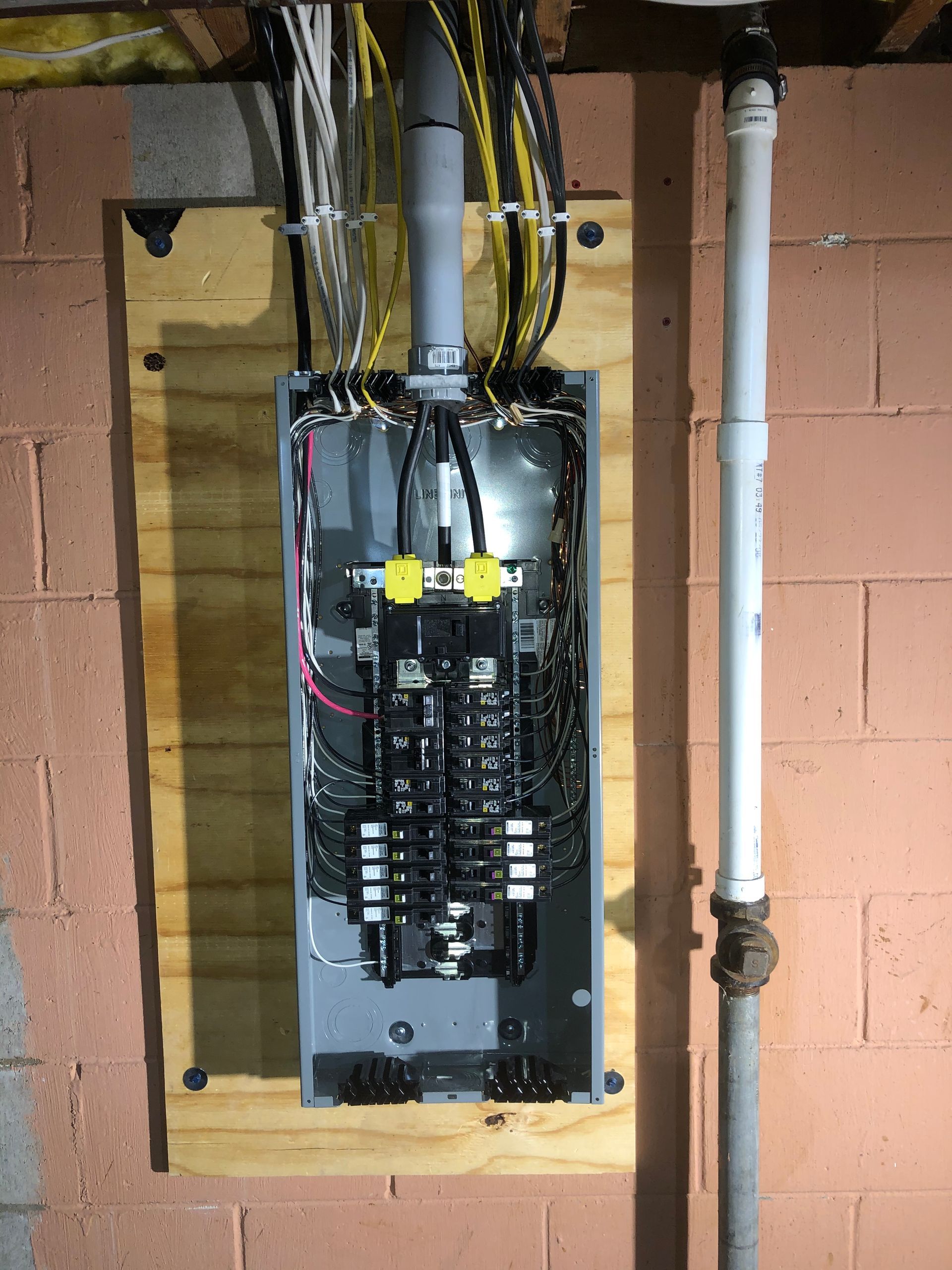Close-up of electrical panel with circuit breakers, wires, and switches in a grey cabinet.