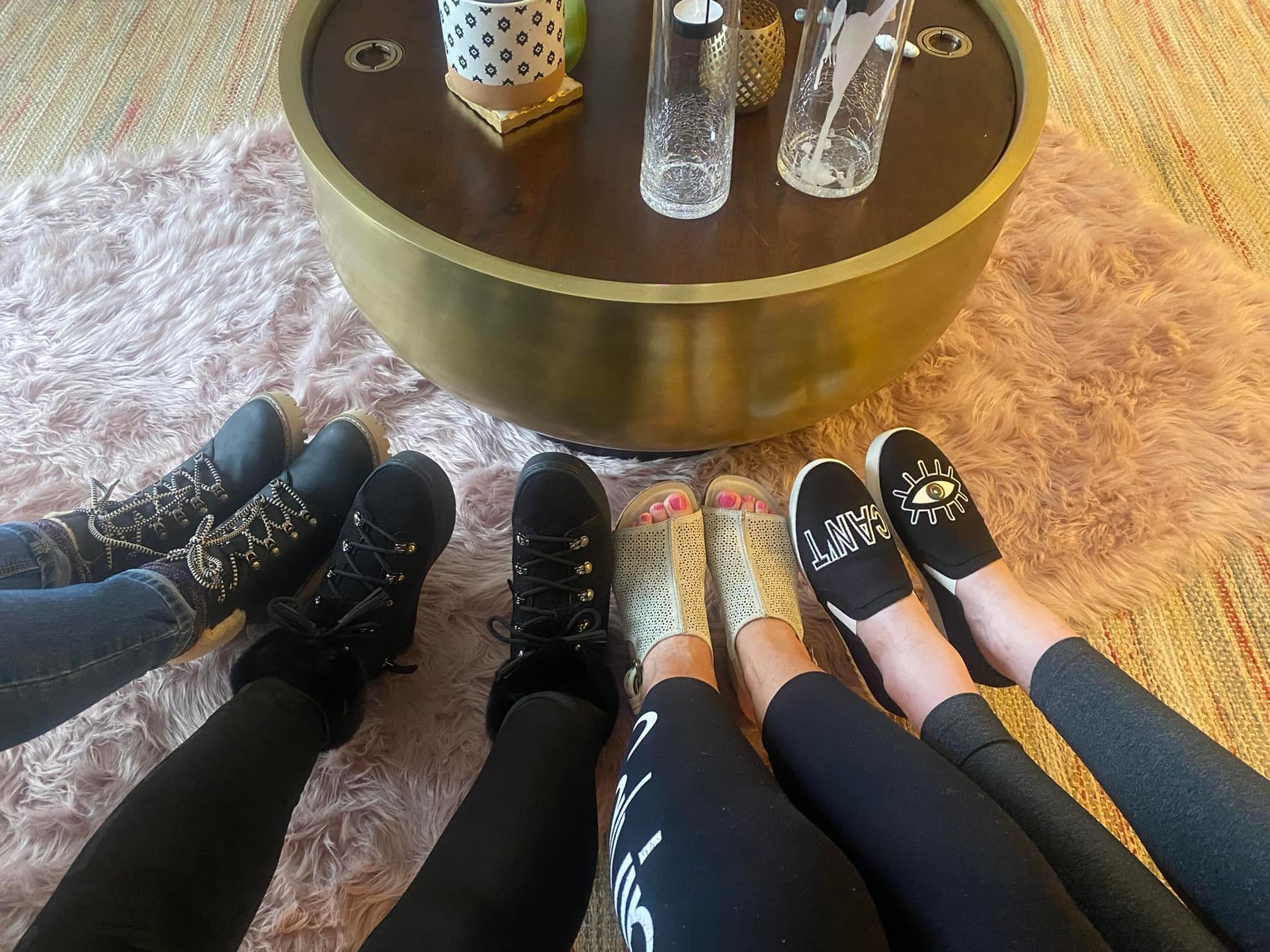 a group of people 's feet are sitting on a rug in front of a coffee table .