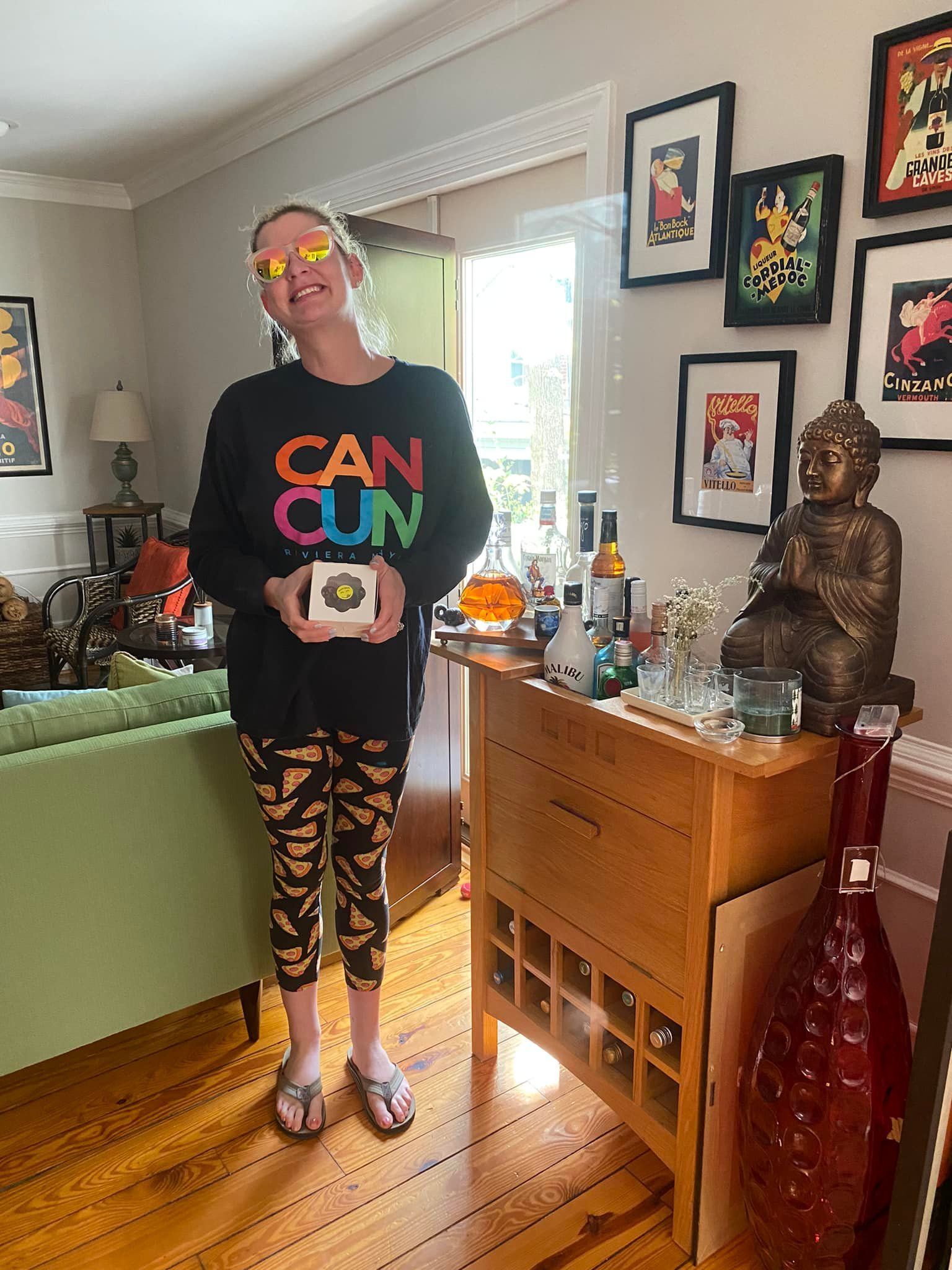 a woman is standing in a living room holding a box .