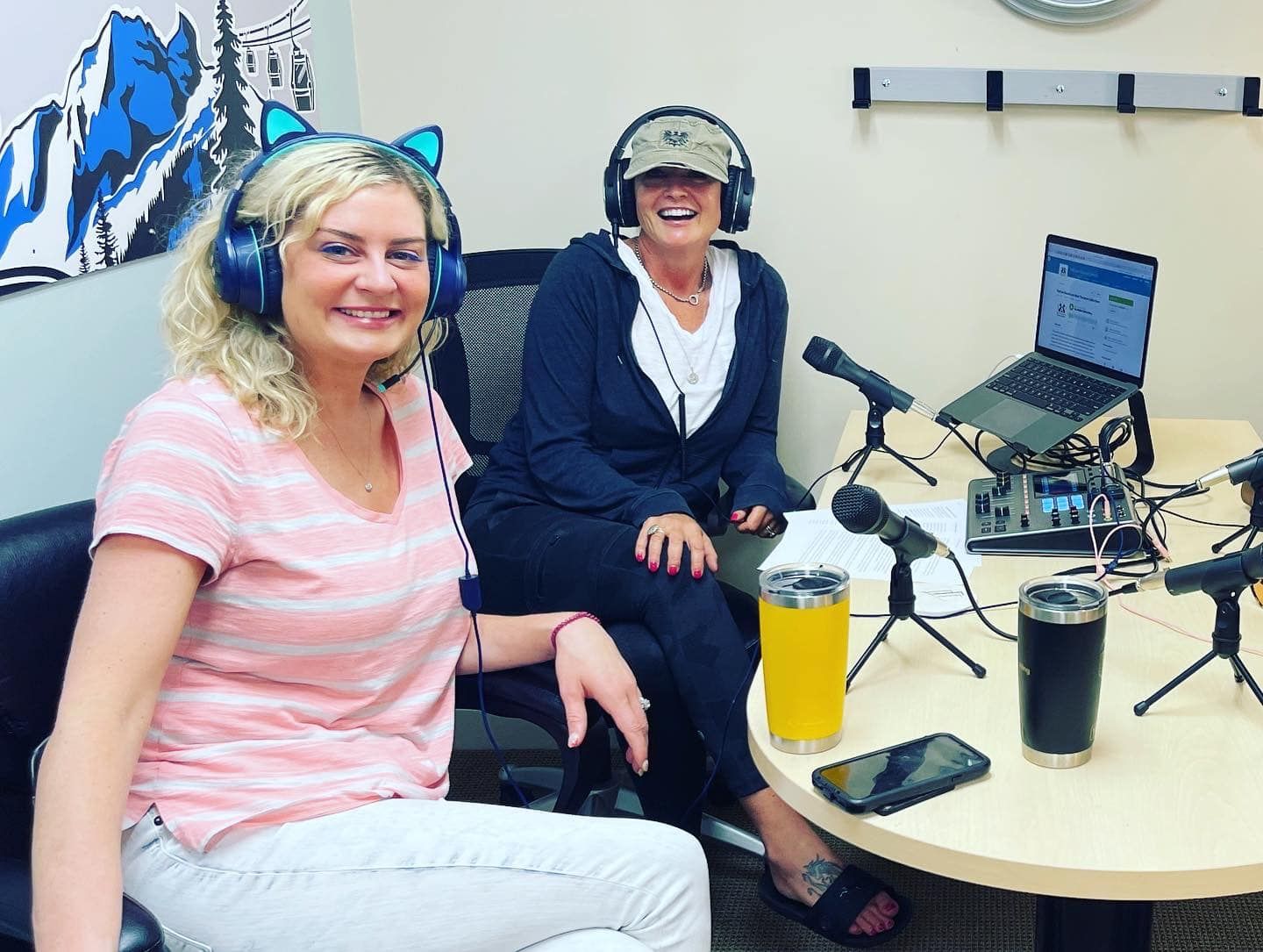 a group of women are sitting around a table with microphones .