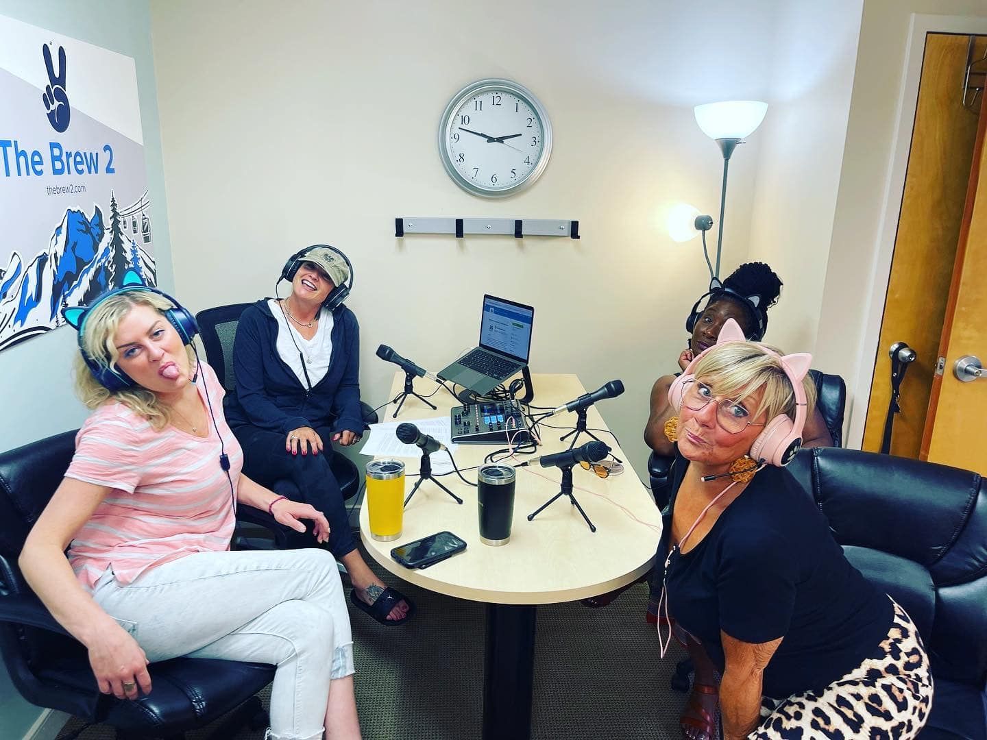 a group of women are sitting around a table wearing headphones .