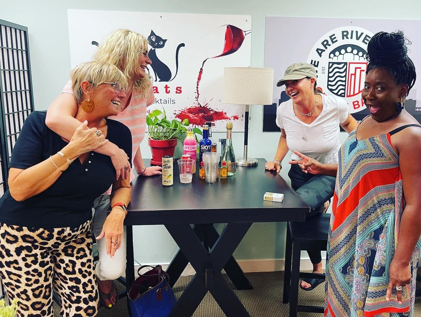 two women standing in front of a sign that says cats cocktails