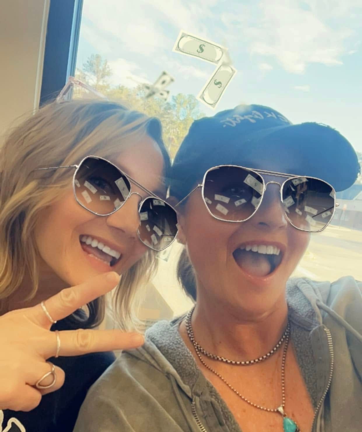 Two smiling women wearing sunglasses. One makes a peace sign. Dollar signs float above.