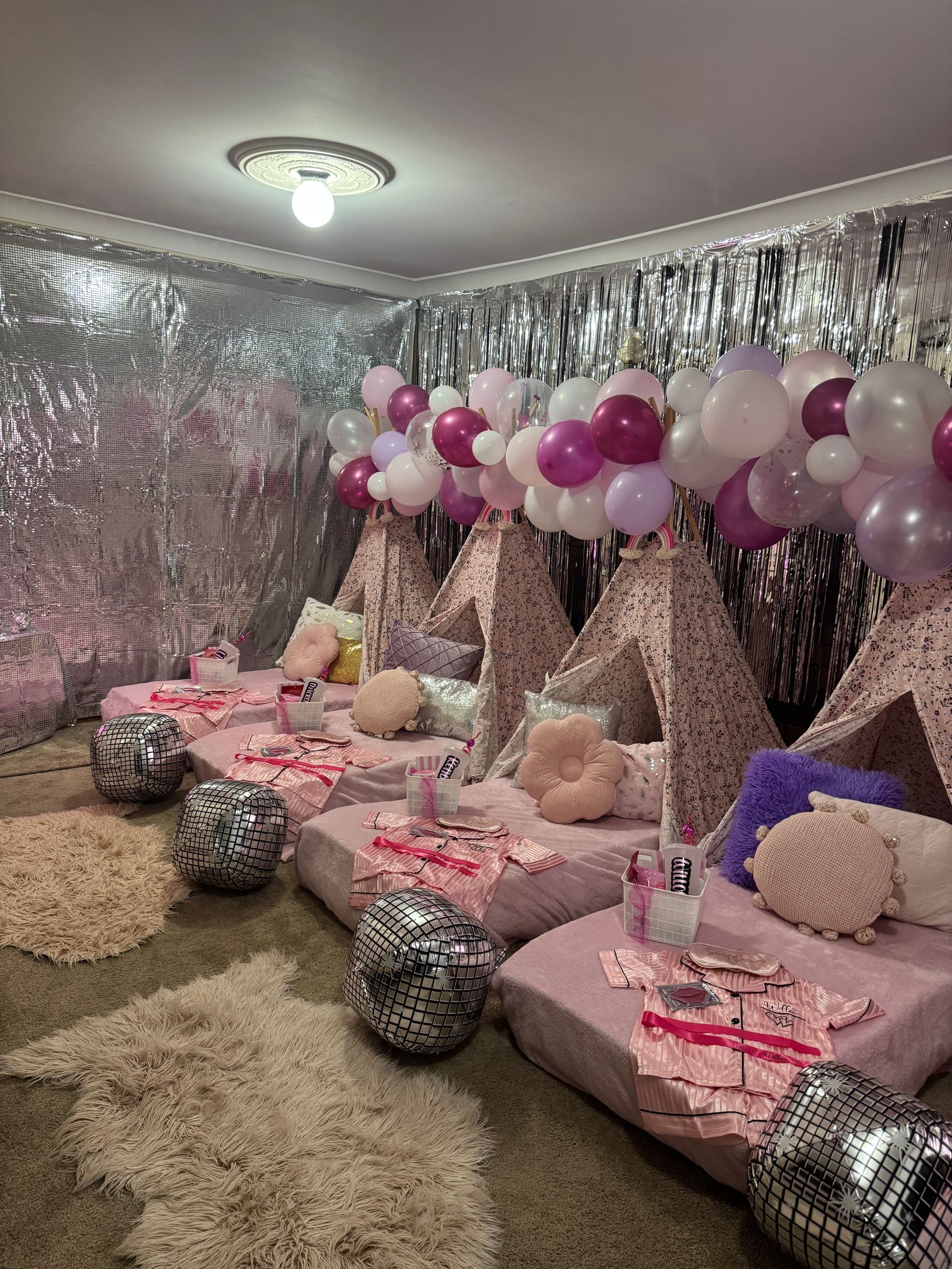Pink and silver balloon party setup with floor cushions, metallic decor, and sequined pillows in a small room — Sweet Parties & Braids in Tatton, NSW